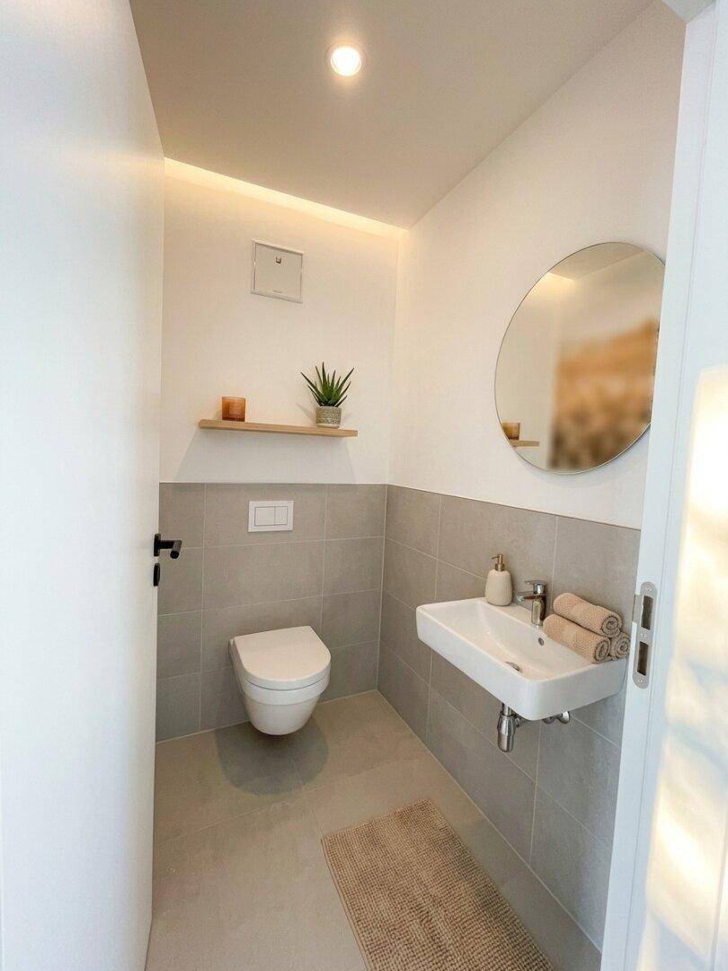 Modernes Gäste-WC mit Wand-WC, Waschbecken und halbhohen Fliesen.