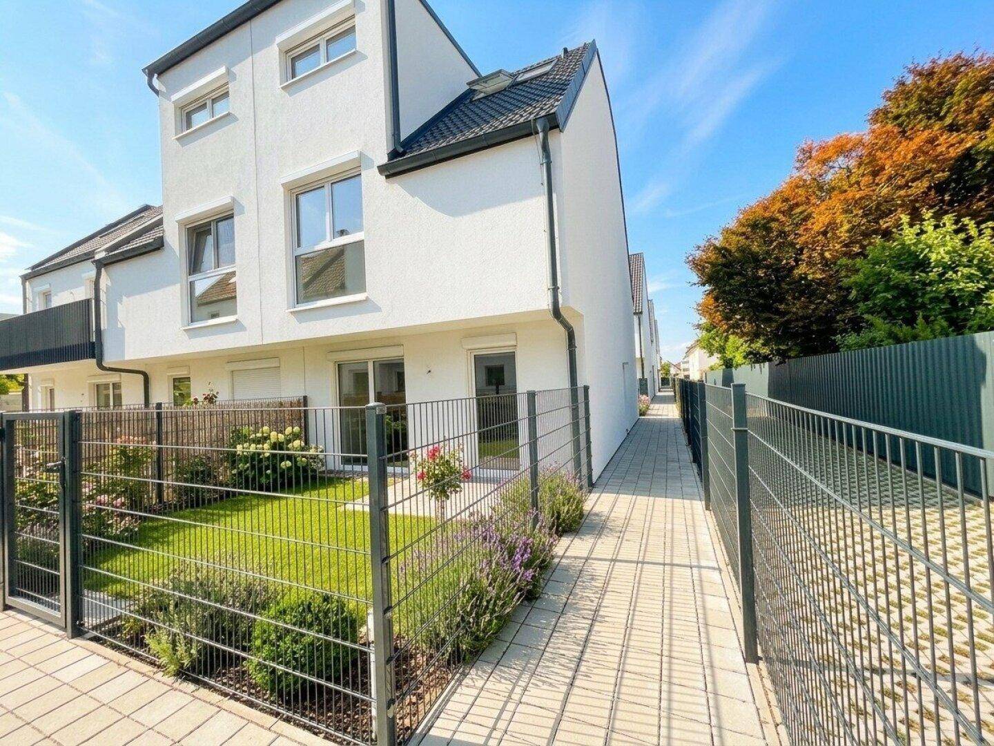 Kleiner, gepflegter Gartenbereich mit Rasen und Blumenbeeten neben dem Reihenhaus.