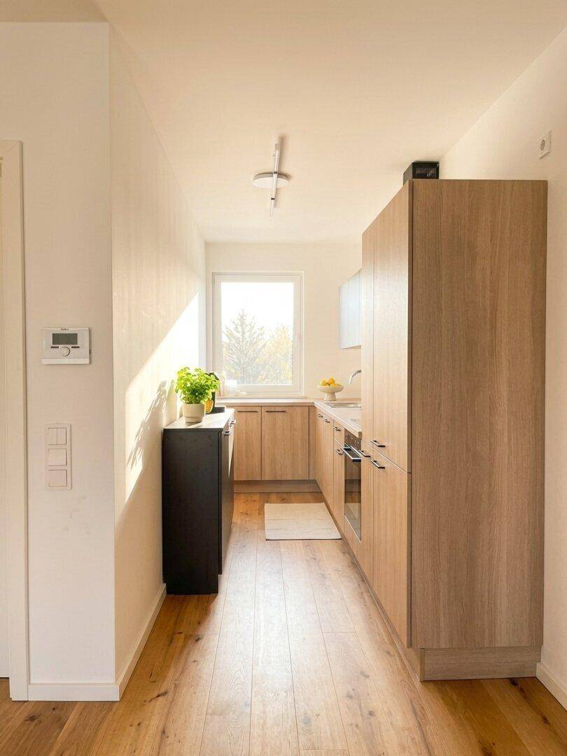 Helle Küche mit Holzfronten, Fenster und ausreichend Arbeitsfläche.