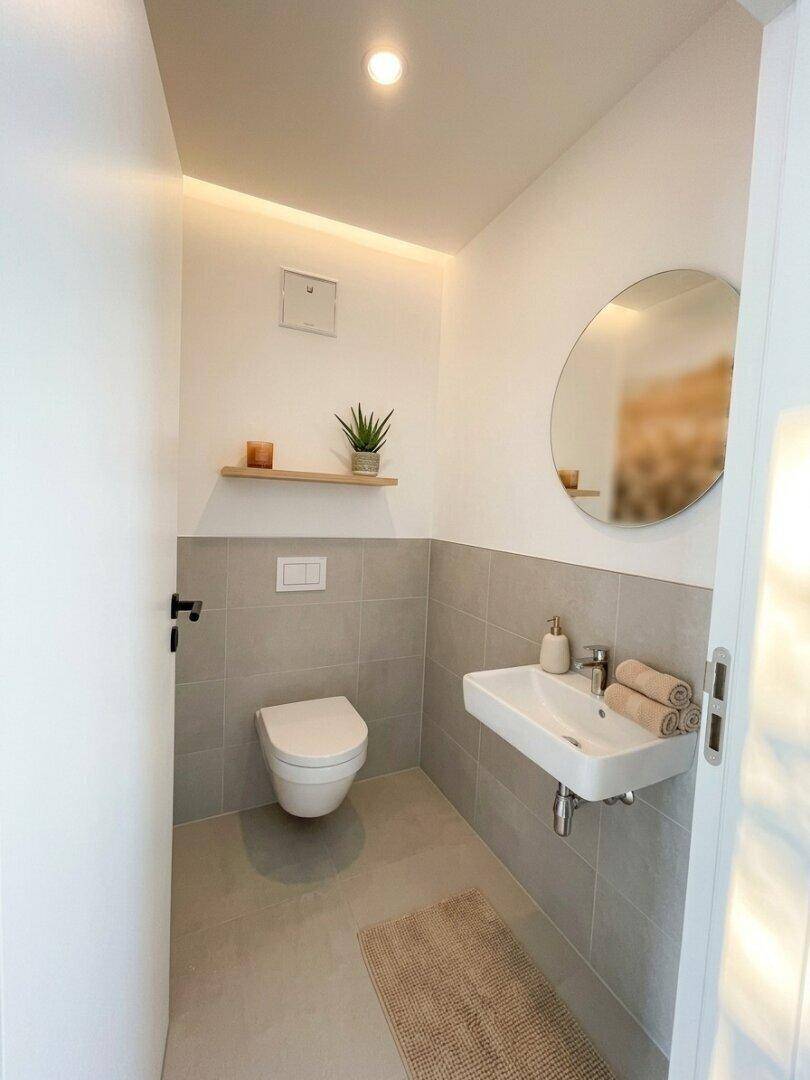 Modernes Gäste-WC mit Wand-WC, Waschbecken und indirekter Beleuchtung.