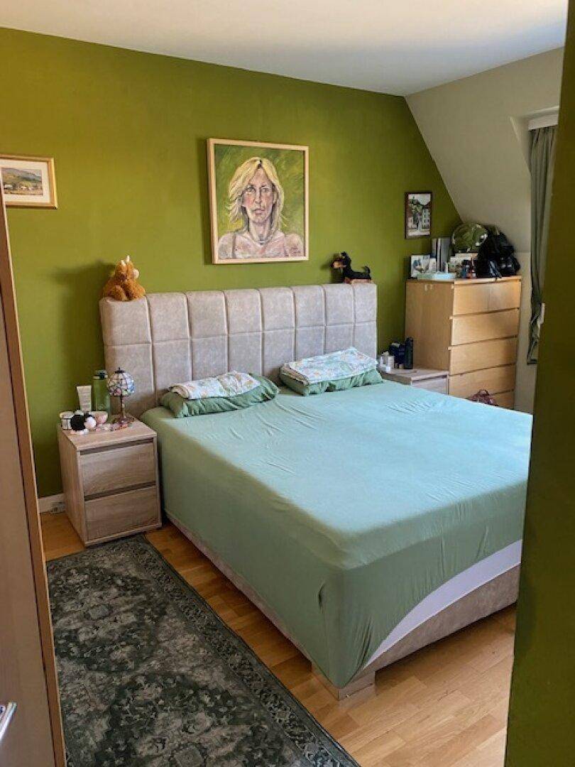 Geräumiges Schlafzimmer mit großem Doppelbett, grünen Wänden und passenden Nachttischen, bietet viel Komfort.