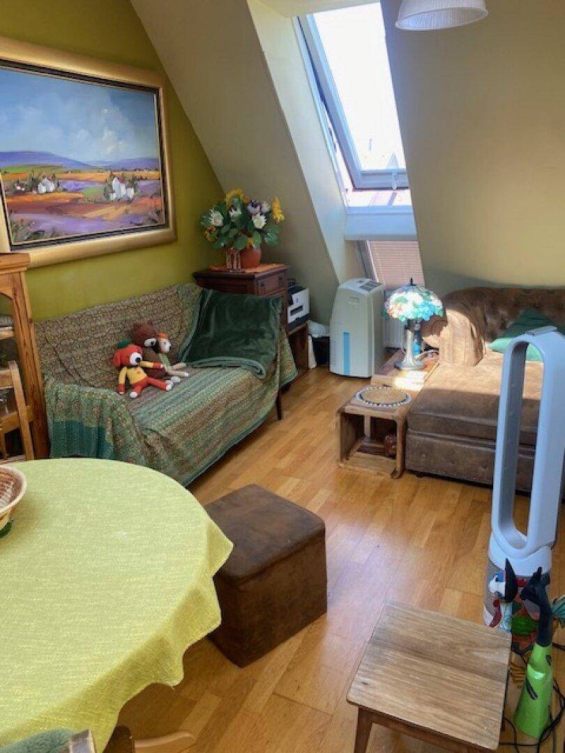 Gemütliches Wohnzimmer im Dachgeschoss mit schrägen Wänden, Sofa und einem großen Dachfenster für viel Licht.