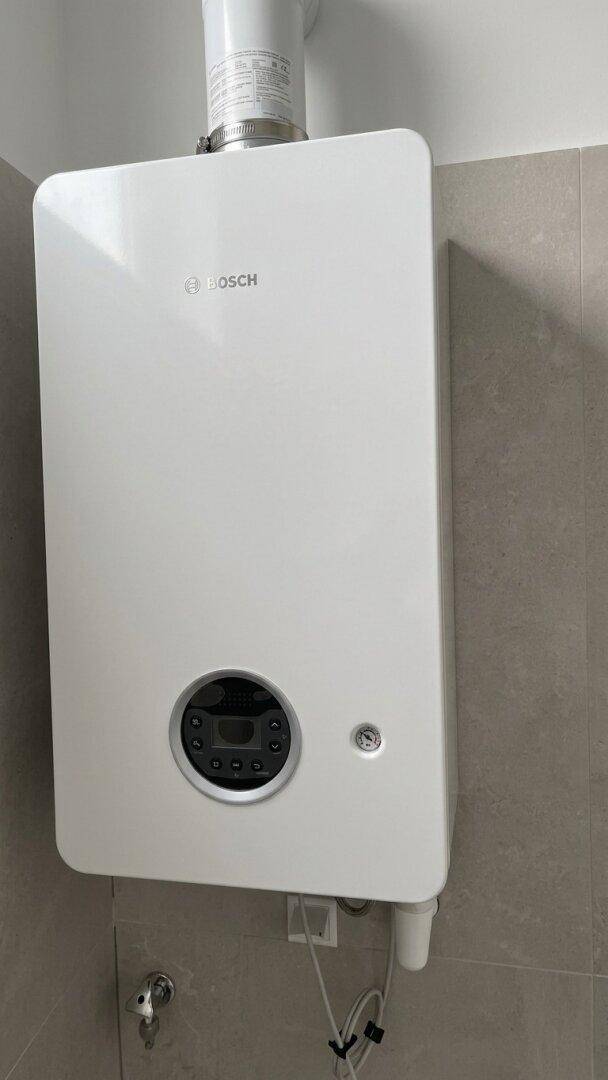 Nahaufnahme eines modernen weißen Bosch-Boilers an einer gefliesten Wand.