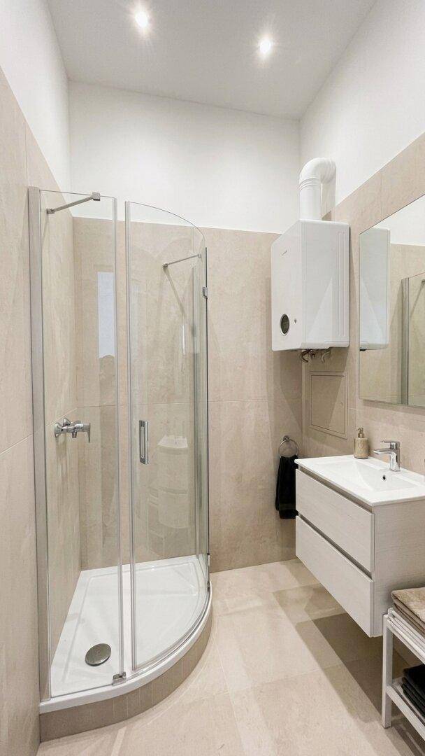 Modernes Badezimmer mit Eckdusche, Waschbeckenunterschrank und einem an der Wand montierten Boiler.