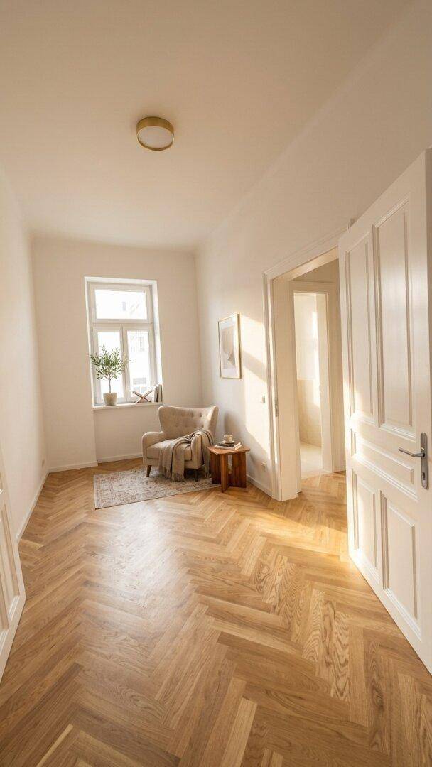 Helles Wohnzimmer mit elegantem Fischgrätparkett, einem bequemen Sessel und natürlichem Lichteinfall durch das Fenster.