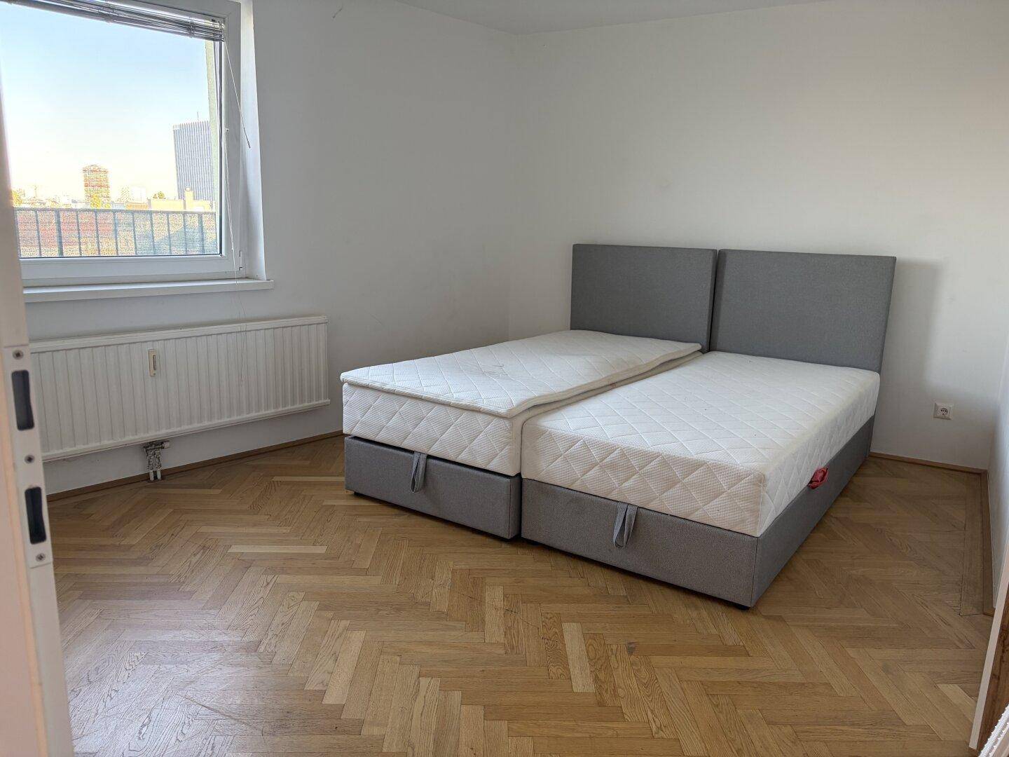 Gemütliches Schlafzimmer mit komfortablem Doppelbett und elegantem Fischgrätparkettboden.