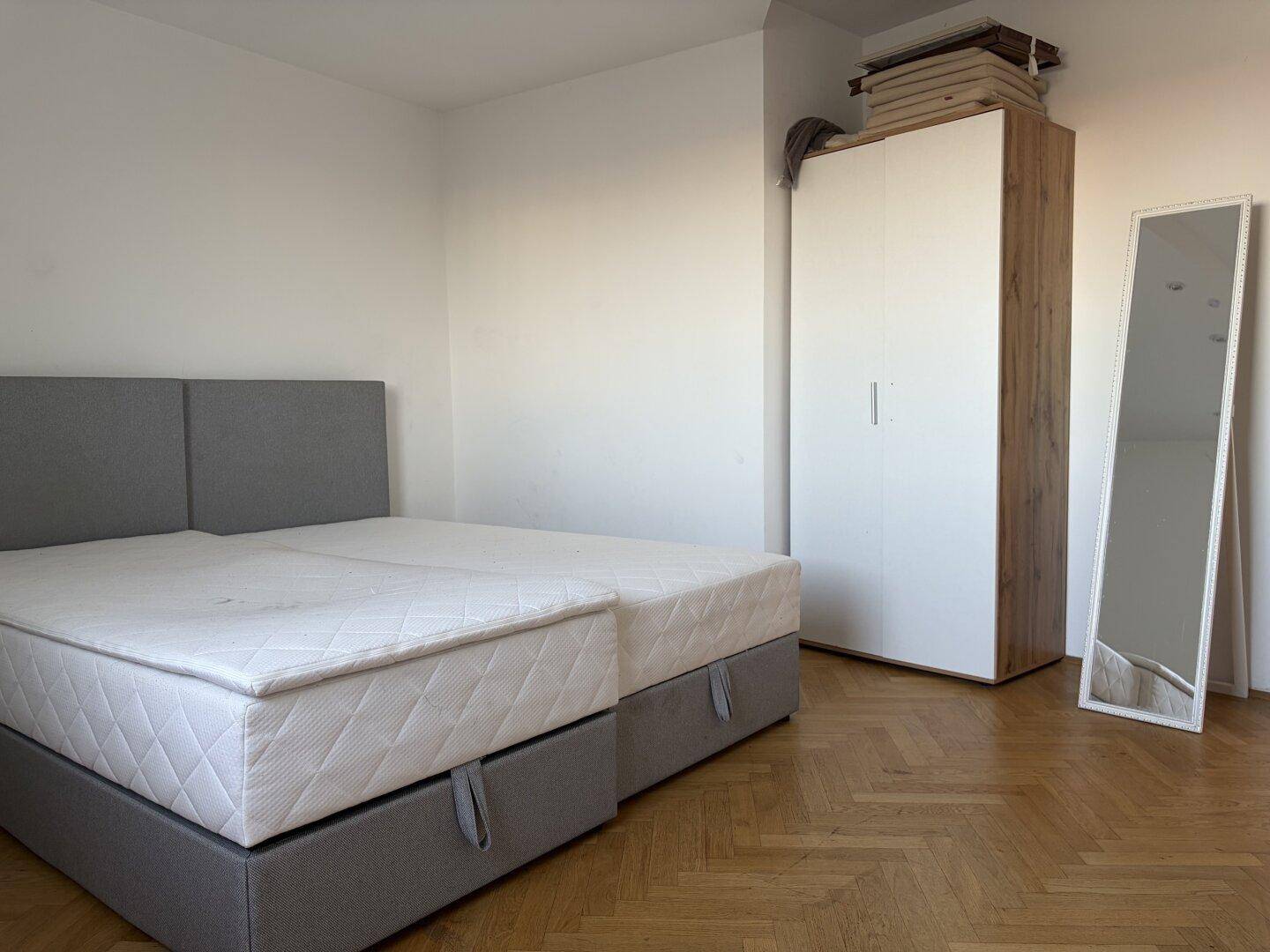 Schlafzimmer mit Doppelbett, geräumigem Kleiderschrank und einem großen Standspiegel.