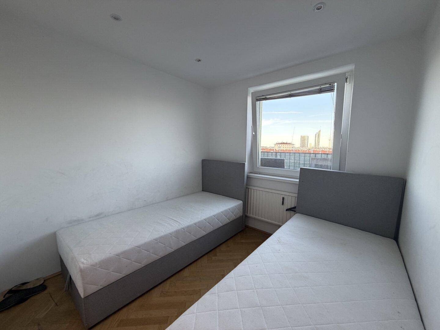 Helles Kinder- oder Gästezimmer mit zwei Einzelbetten und Blick auf die Umgebung.