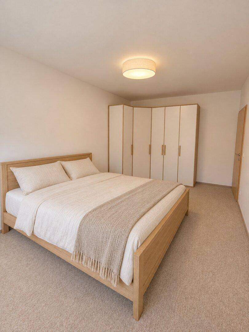 Gemütliches Schlafzimmer mit hellem Holzbett, Einbauschränken und beigem Teppichboden.