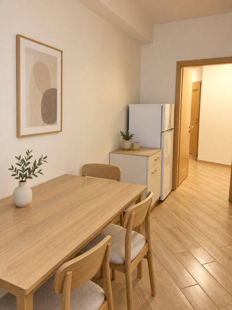 Heller Essbereich mit Holztisch, Stühlen und einem Kühlschrank im Hintergrund.