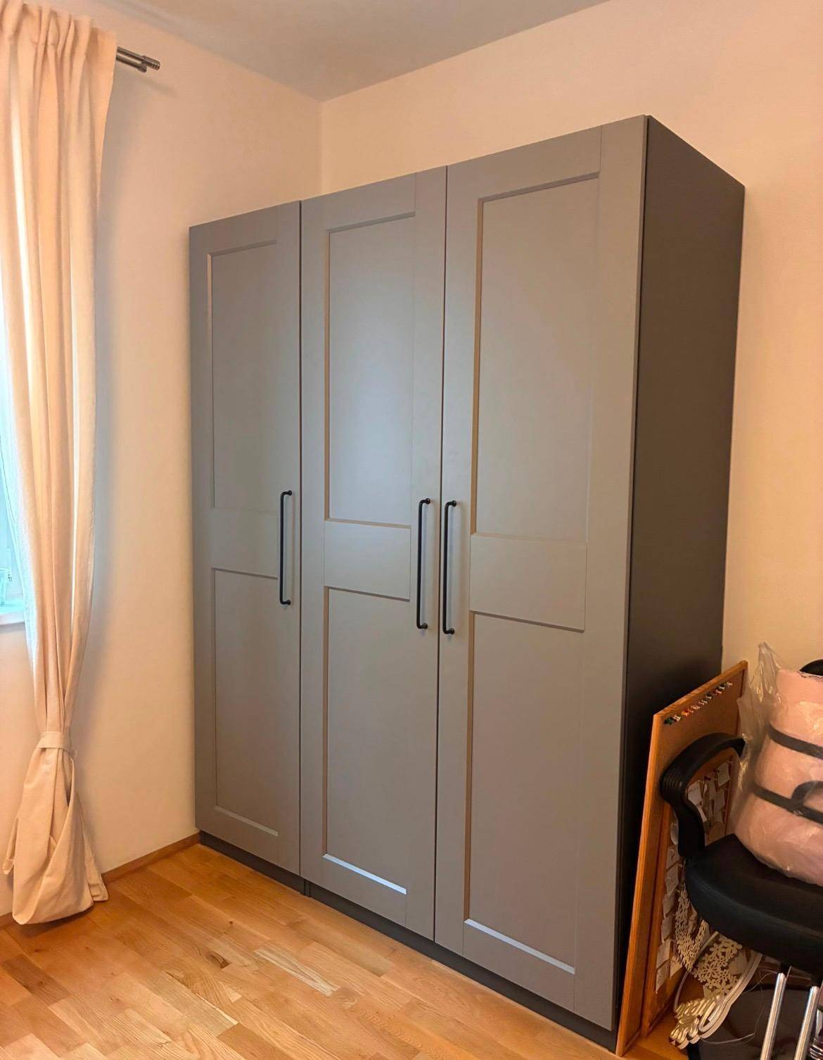 Schlafzimmer mit großem, modernem grauen Kleiderschrank und Holzboden, gut organisiert und hell.