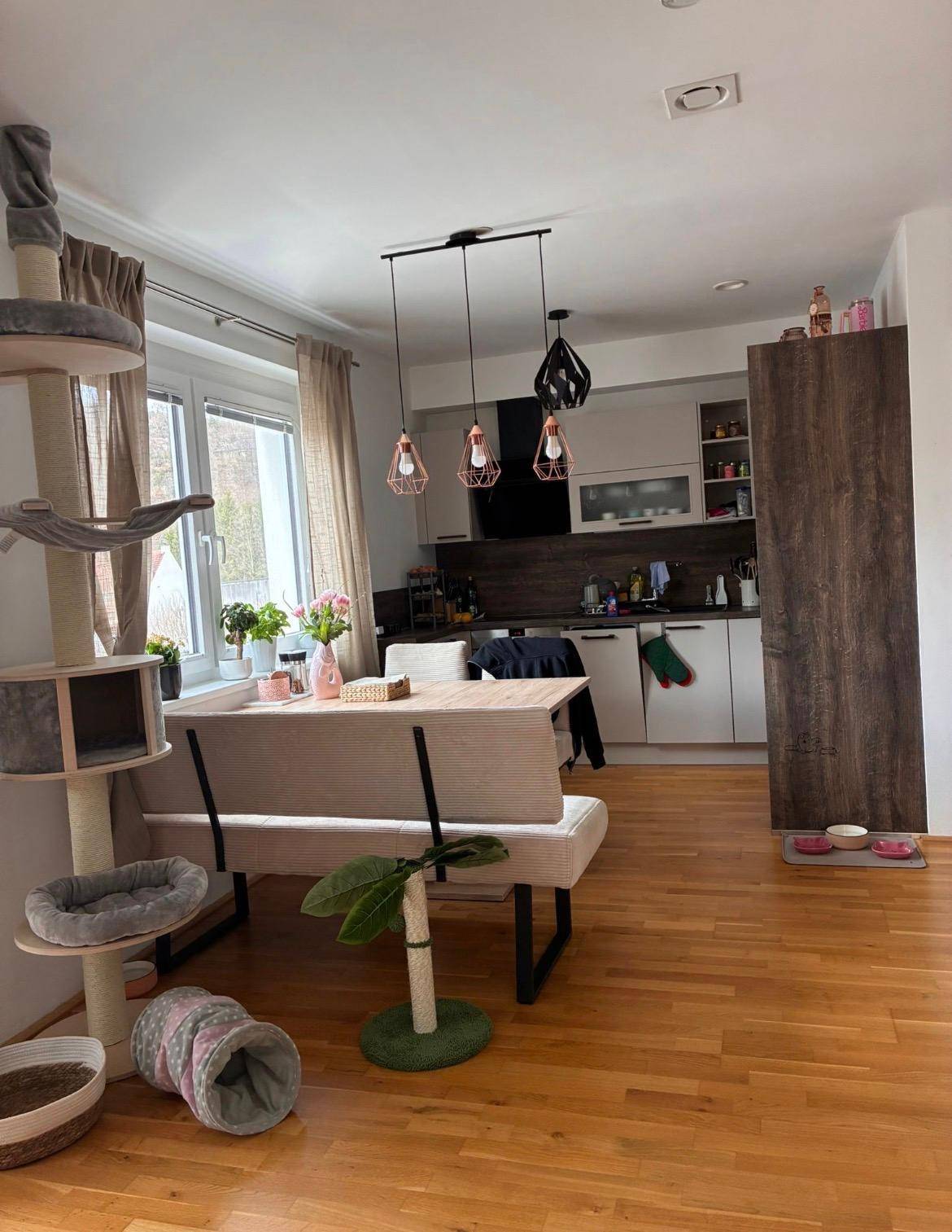 Offene Küche mit Essbereich, Holzboden und modernen Hängeschränken, hell und funktional gestaltet.