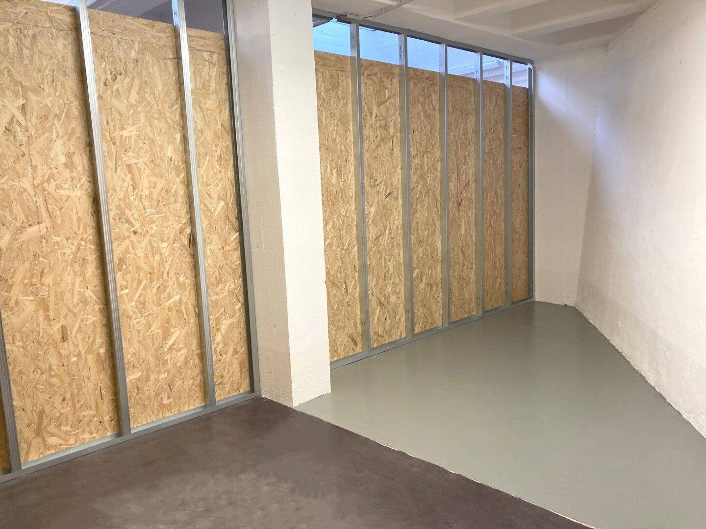 Innenansicht eines Lagerraums mit OSB-Plattenwänden und Metallrahmen, ausgestattet mit einem robusten Betonboden.