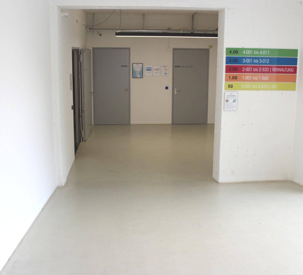 Heller Flur in einem Geschäftsgebäude mit mehreren Türen und einem Etagenverzeichnis an der Wand.