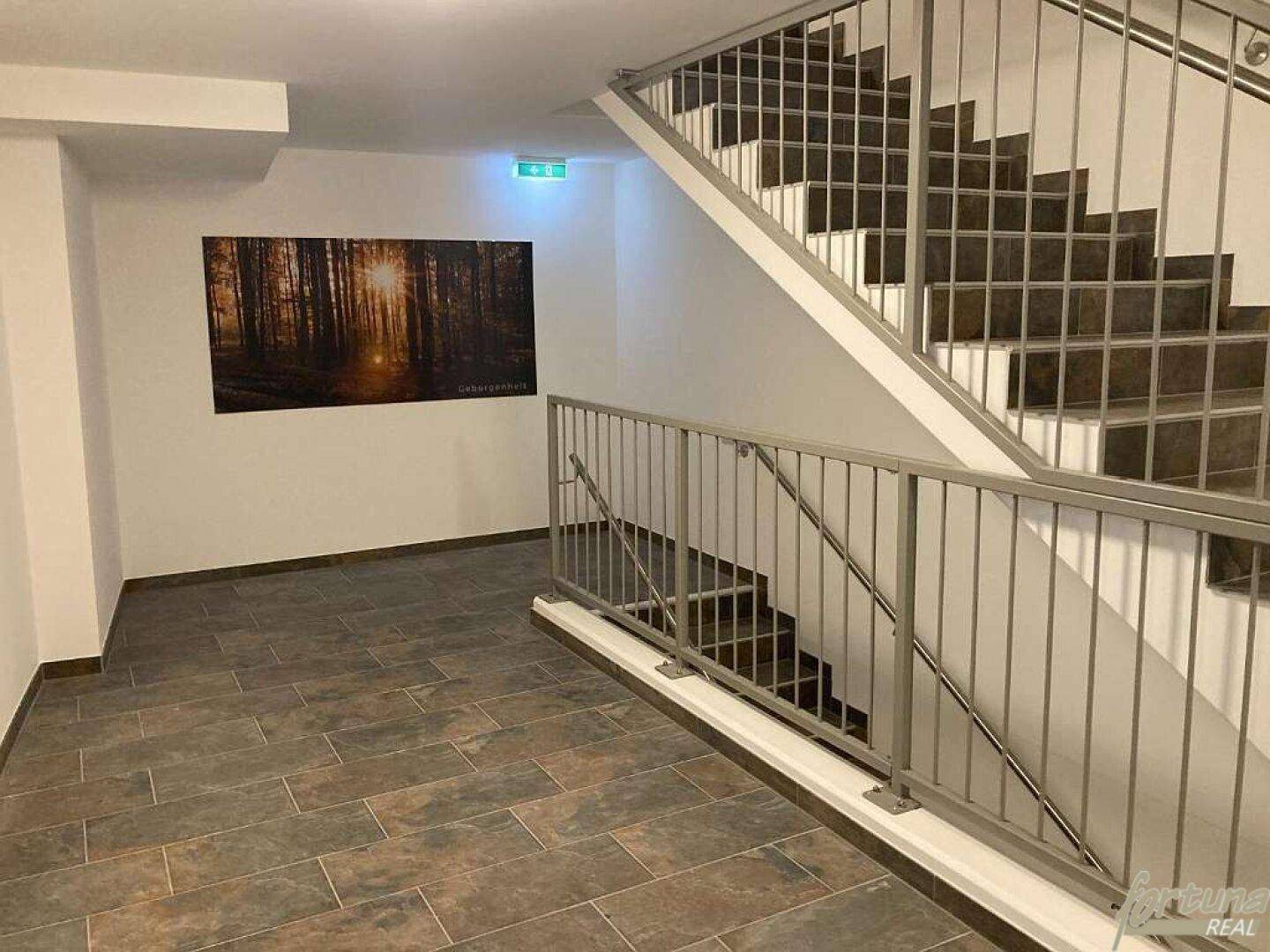 Treppenhaus mit modernem Geländer und Fliesenboden im Gemeinschaftsbereich des Gebäudes.