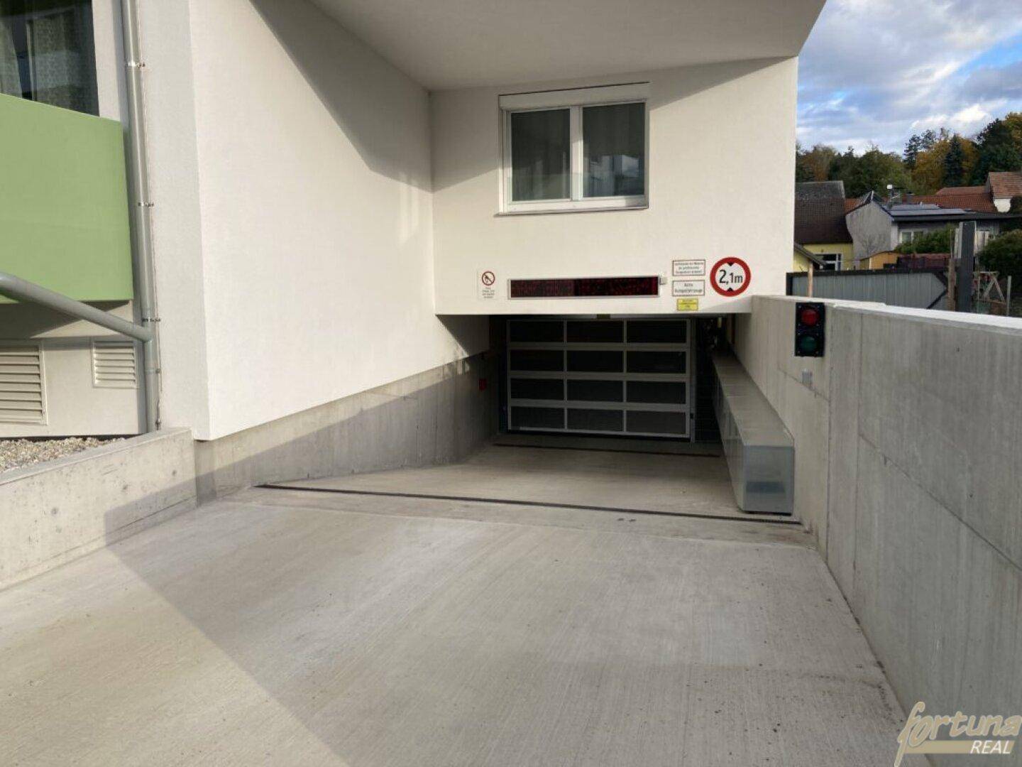 Einfahrt zur Tiefgarage des Wohnkomplexes mit Höhenbegrenzung und Ampelsystem.