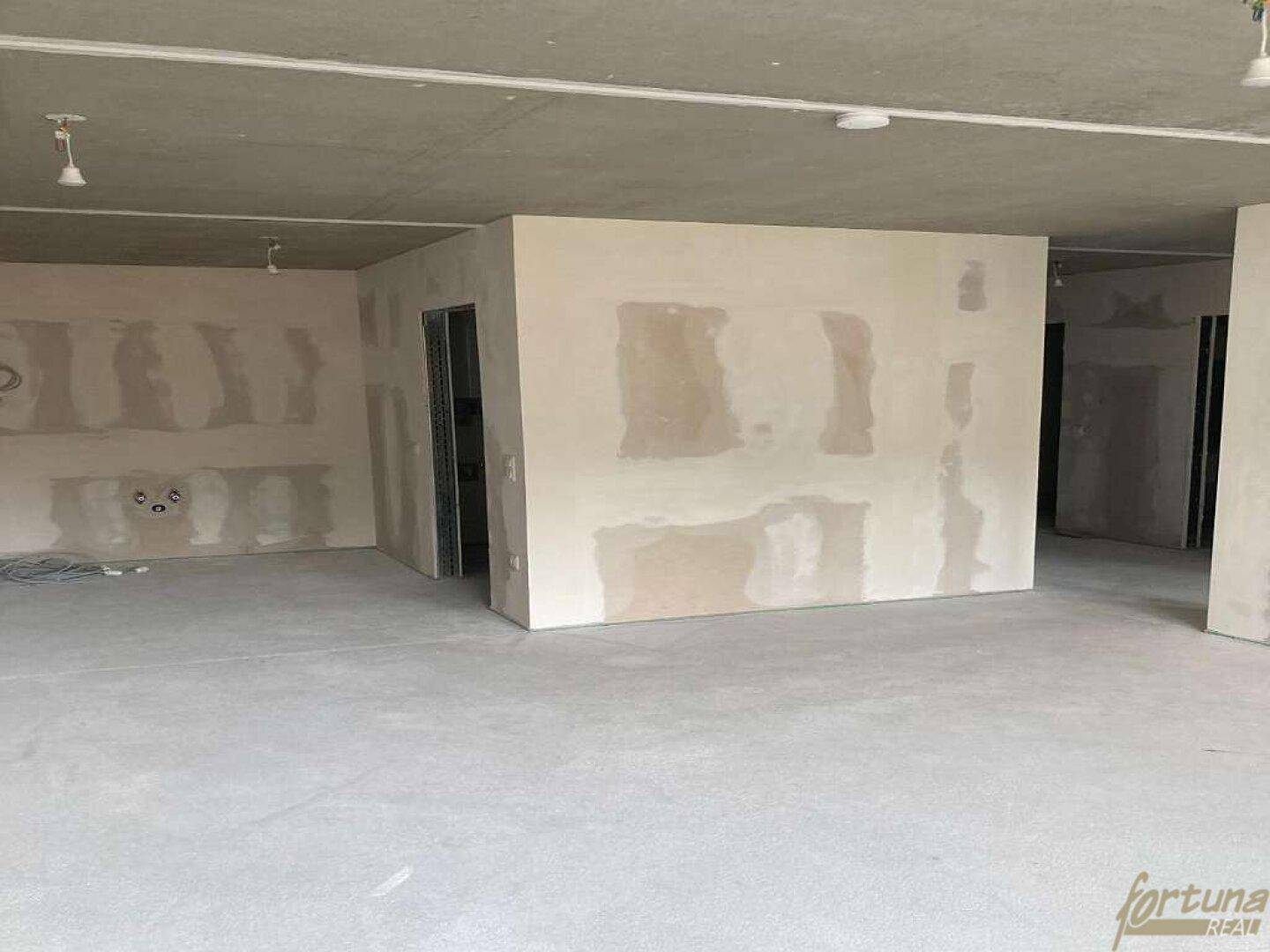 Rohbau eines Innenraums mit unverputzten Wänden und Betonboden, bereit für den Ausbau.