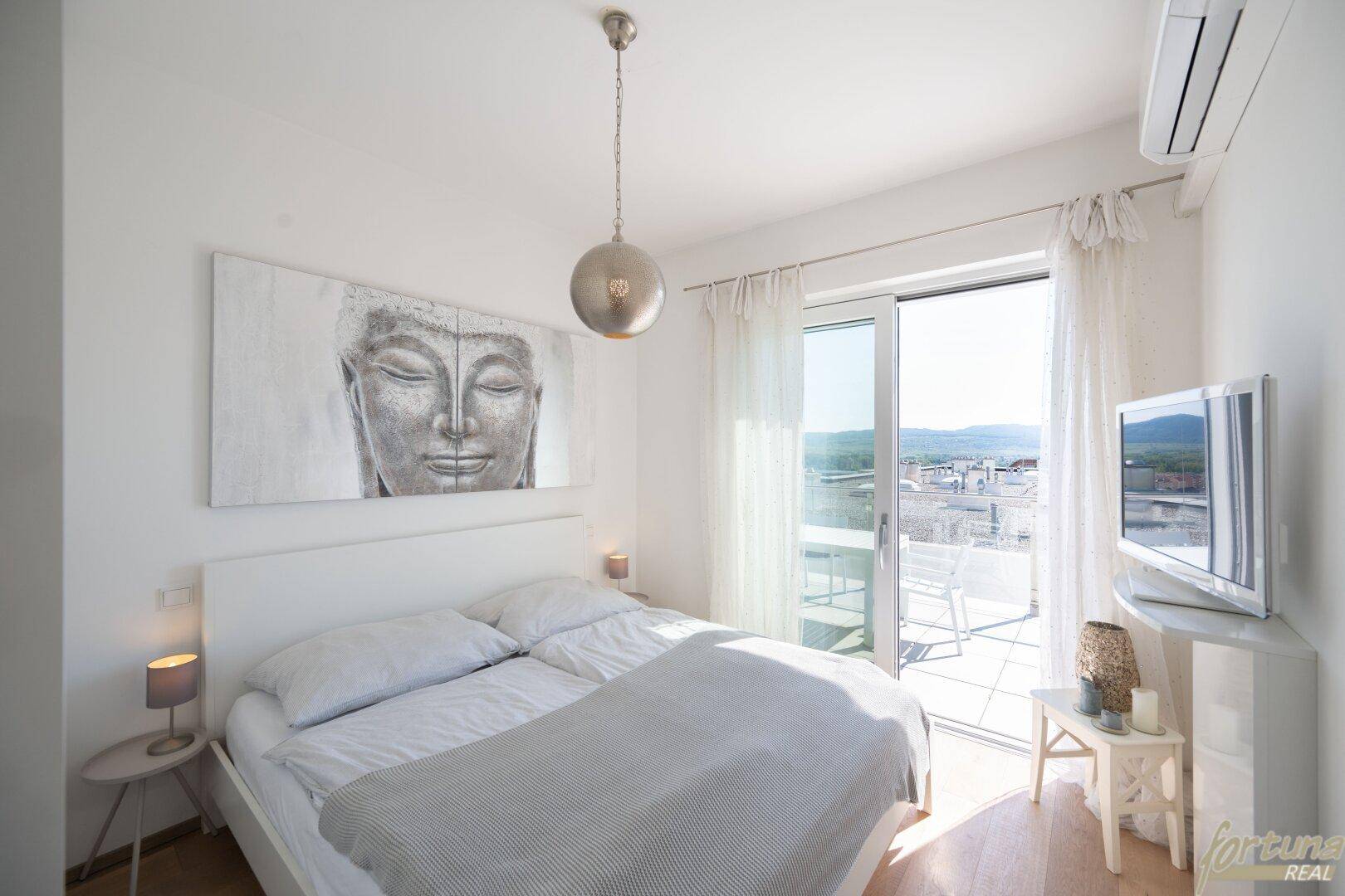 Helles Schlafzimmer mit Doppelbett, Klimaanlage und direktem Zugang zu einem sonnigen Außenbereich.