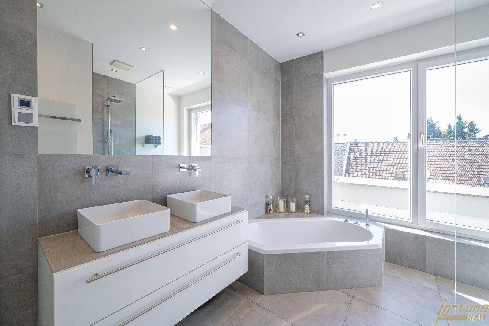 Elegantes Badezimmer mit zwei Aufsatzwaschbecken, Eckbadewanne und großen Fenstern für viel Tageslicht.