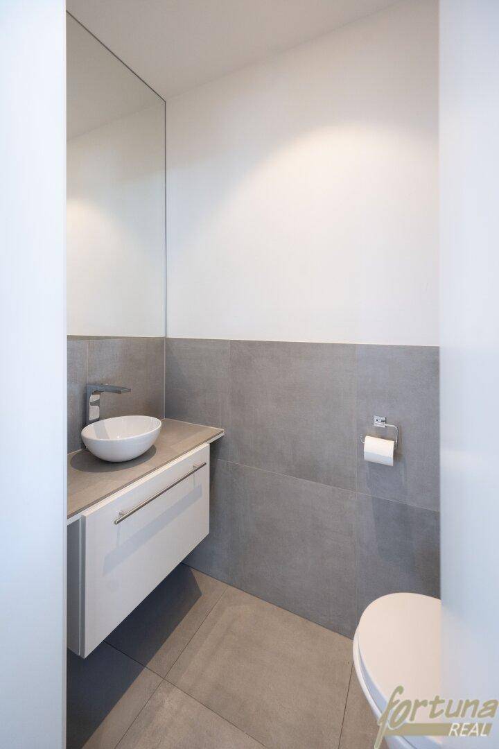 Modernes Gäste-WC mit Wand-WC, Aufsatzwaschbecken und grauen Fliesen an den Wänden.