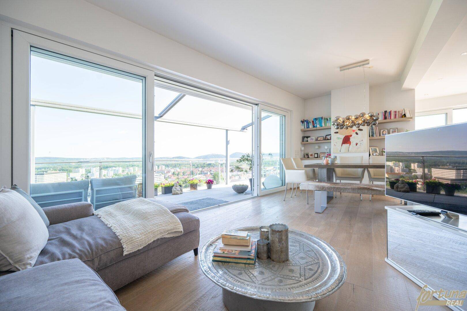 Geräumiger Wohnbereich mit bequemer Couch, Couchtisch und Essbereich im Hintergrund, mit Zugang zur Terrasse.