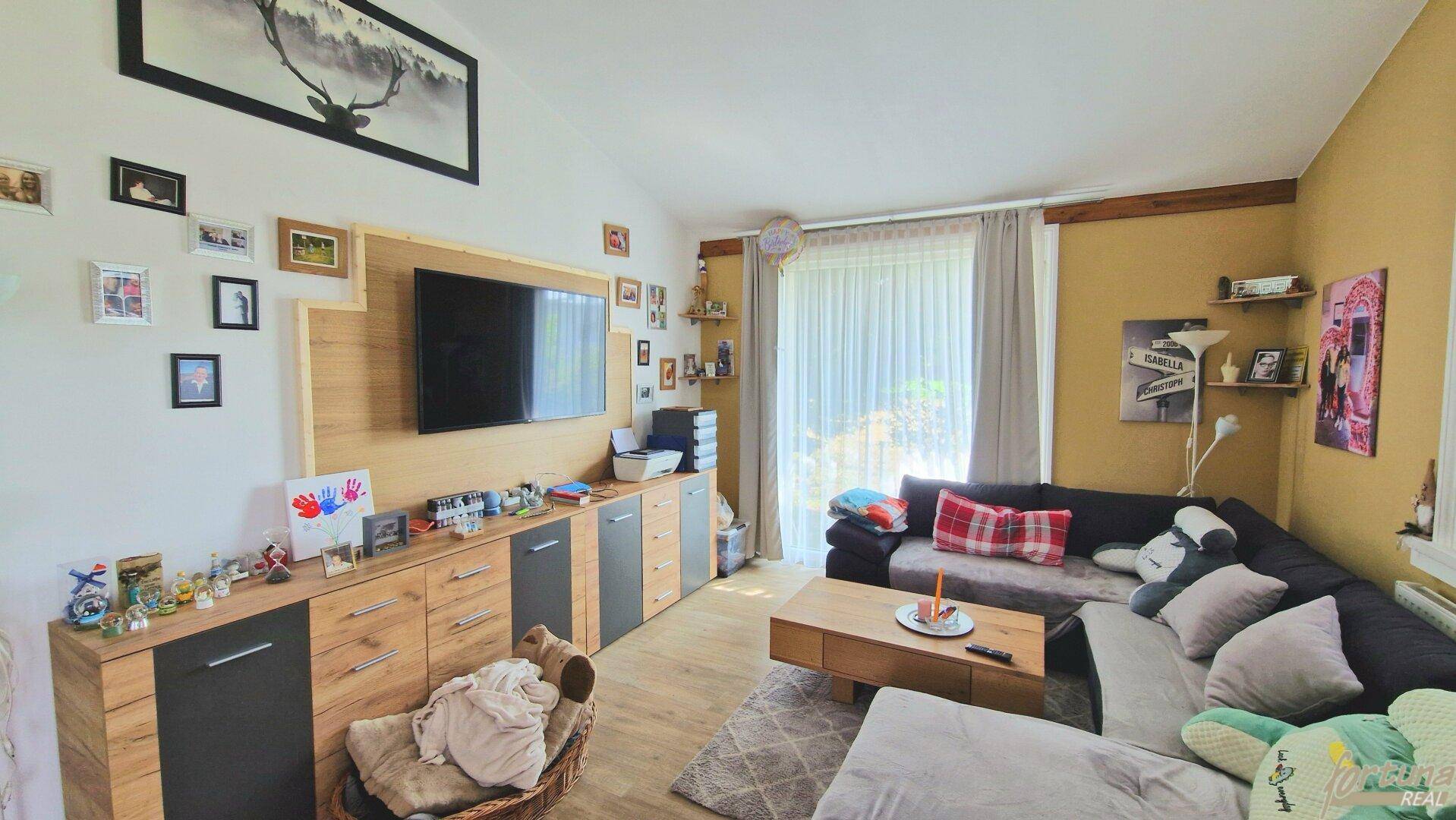 Geräumiges Wohnzimmer mit großem Sofa, TV-Möbel und vielen persönlichen Dekorationen.
