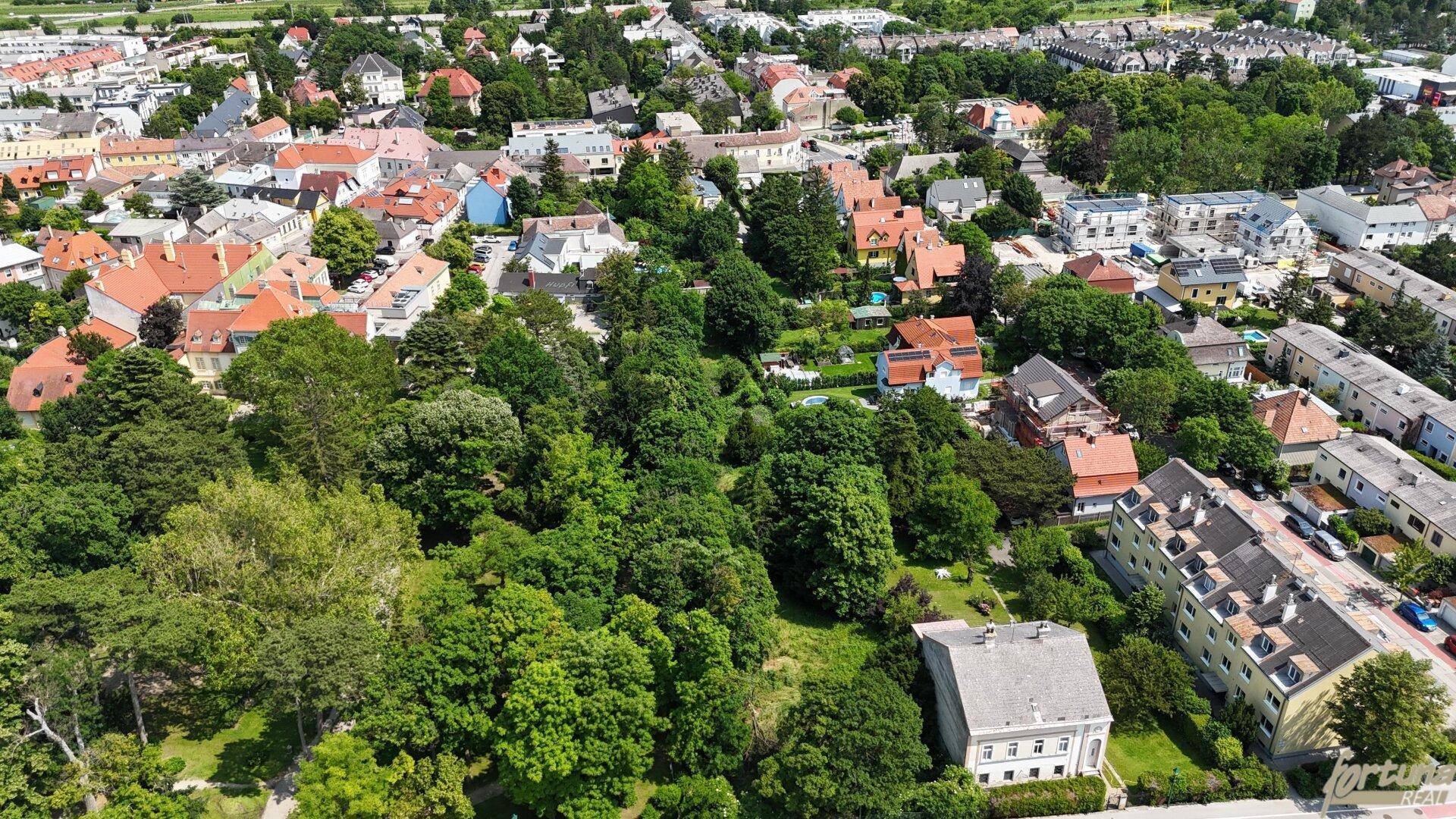Weitläufige Luftaufnahme eines Wohngebiets mit zahlreichen Häusern und üppiger Vegetation im Sommer.