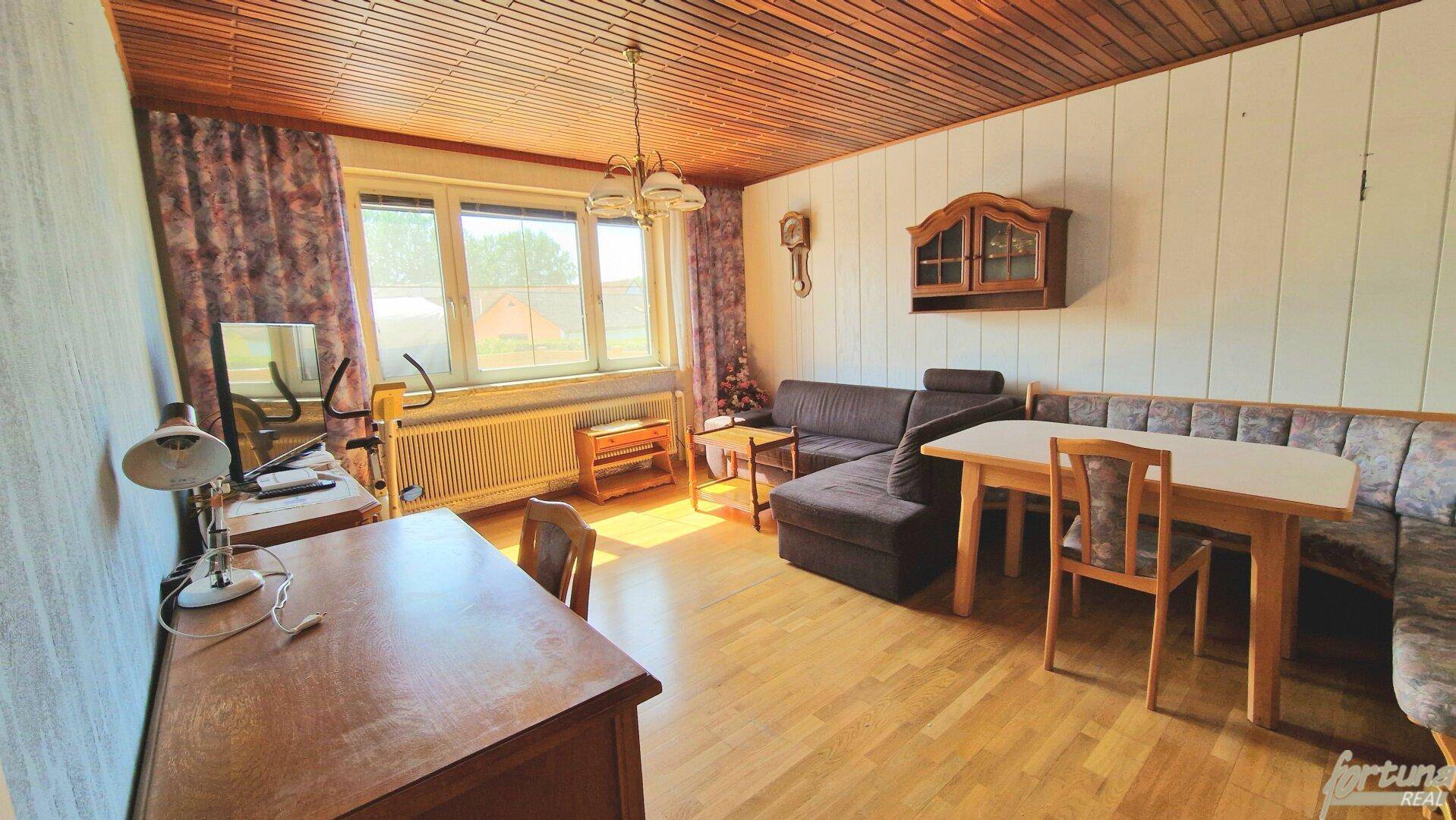 Helles Wohn-Esszimmer mit Holzdecke, Parkettboden und traditionellen Möbeln, gut gepflegt.