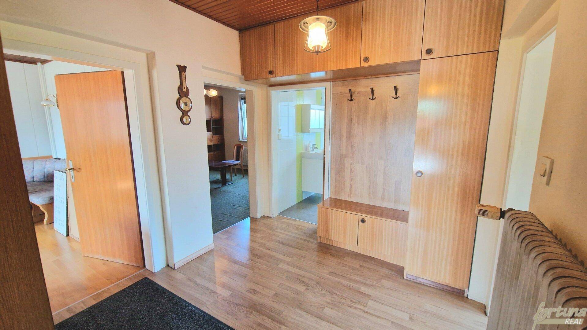 Heller Flur mit Holzvertäfelung, Einbauschränken und Parkettboden, verbindet verschiedene Räume.