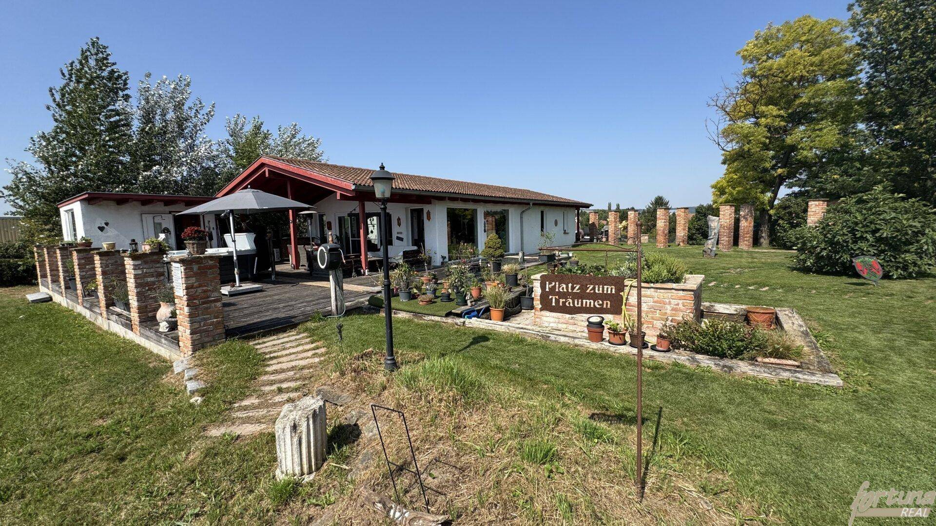 Weitläufiger Gartenbereich mit Terrasse, Sitzgelegenheiten und einem Schild "Platz zum Träumen".
