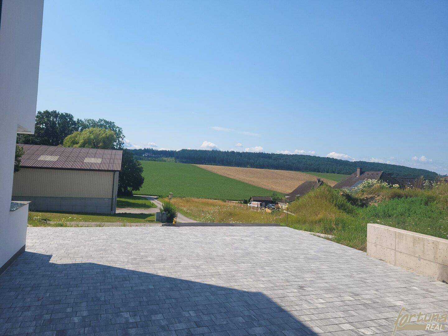 Großer gepflasterter Bereich mit weitem Blick über die umliegende Landschaft und Felder.