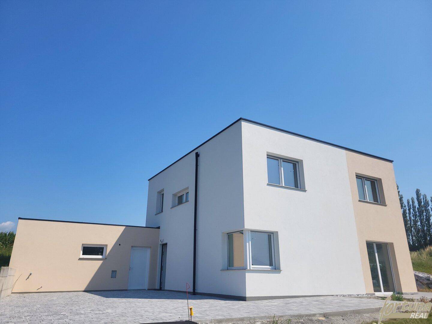 Modernes Einfamilienhaus mit heller Fassade und klaren Linien unter blauem Himmel.