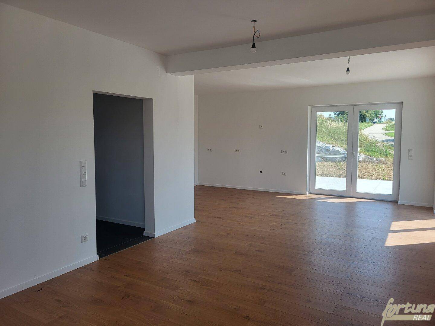 Offener Wohnbereich mit Holzboden und viel Tageslicht, bereit für individuelle Gestaltung.