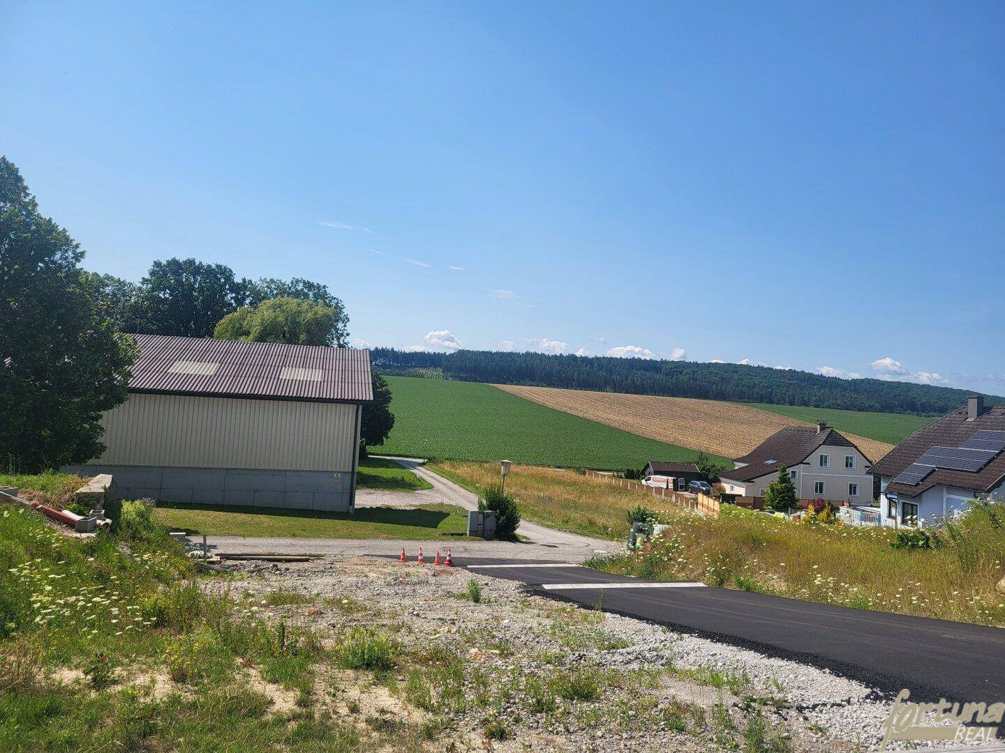 Panoramablick über die ländliche Landschaft mit Feldern, Wäldern und vereinzelten Häusern.