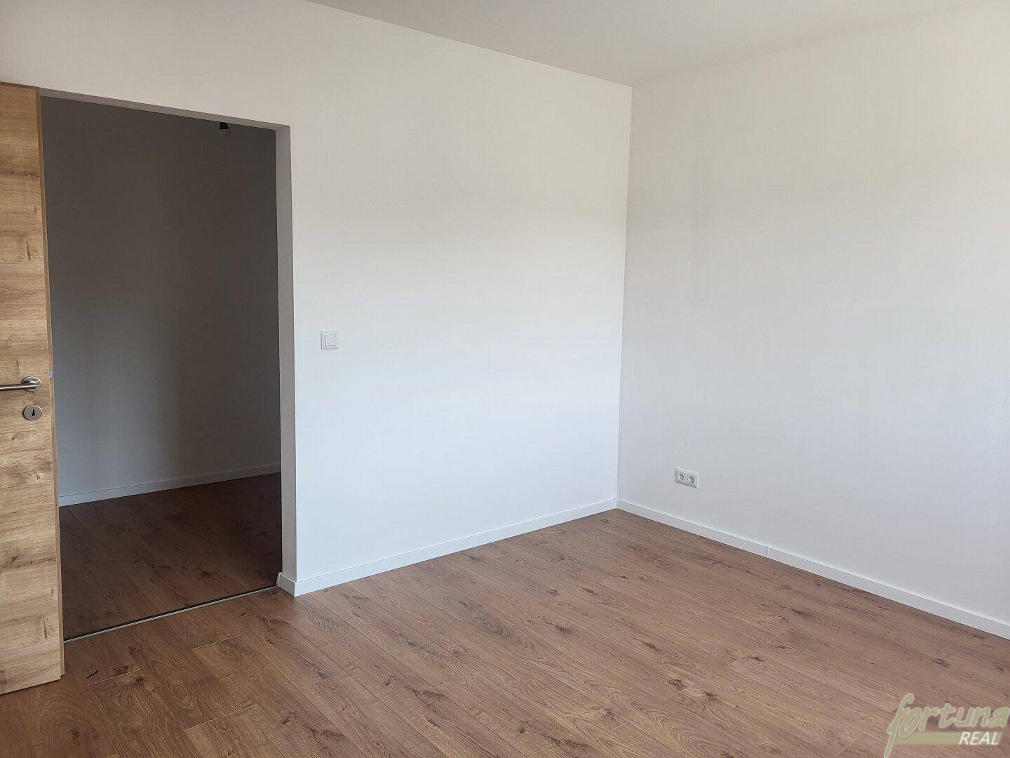 Leeres Zimmer mit Holzboden und weiß gestrichenen Wänden, bereit zur Einrichtung.