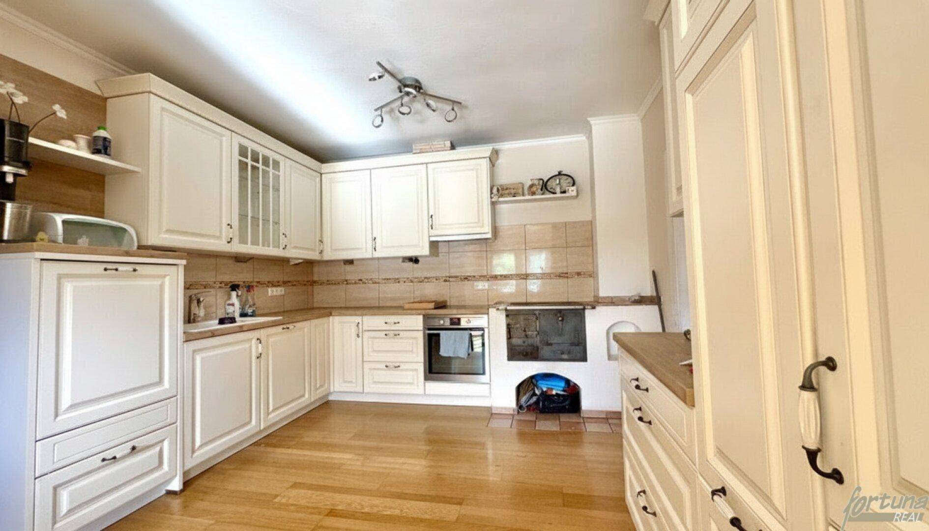 Traditionelle Küche mit hellen Holzschränken, Holzboden und integriertem Ofen.