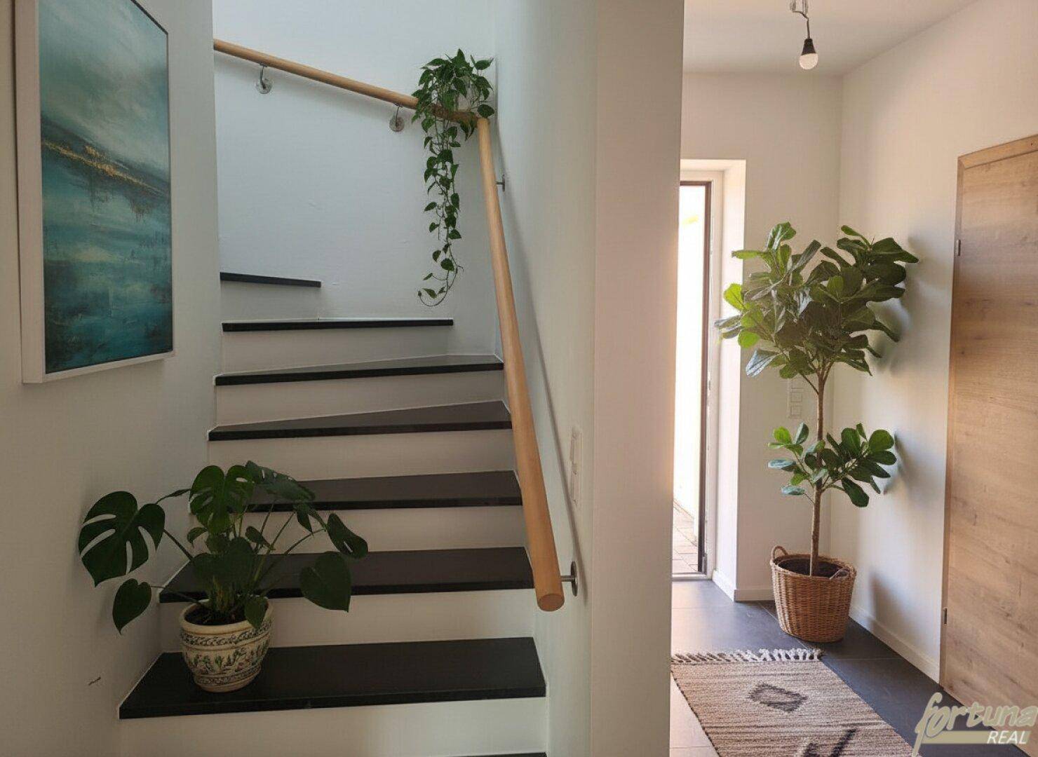 Heller Eingangsbereich mit Treppe, Holzgeländer und dekorativen Pflanzen.