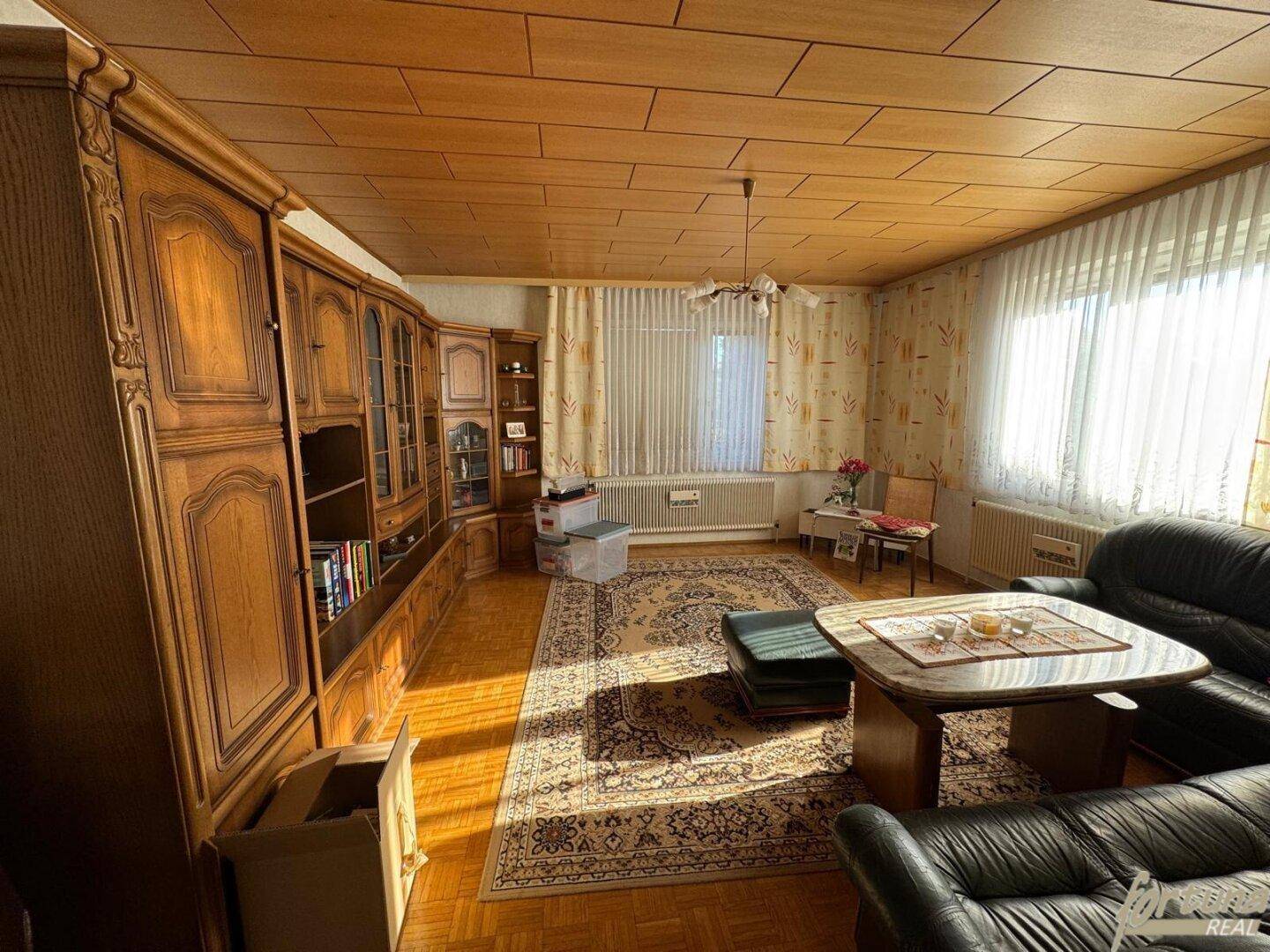 Helles Wohnzimmer mit Holzdecke, Parkett und traditionellen Holzmöbeln.