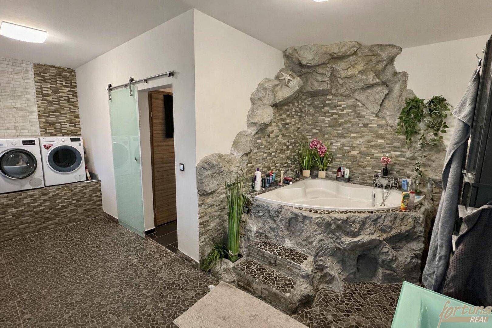 Großes Badezimmer mit Whirlpool, Waschmaschinen und dekorativen Steinakzenten.