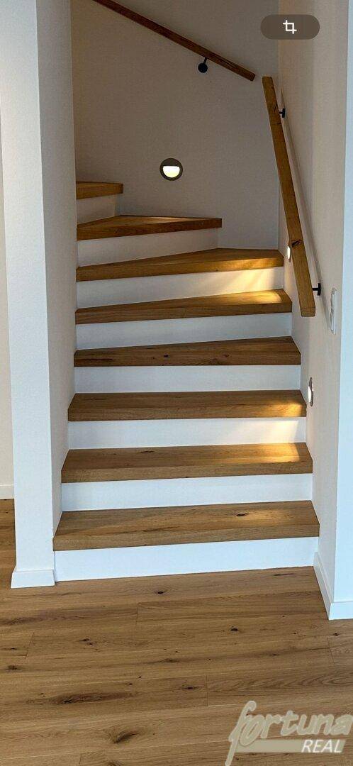 Moderne Holztreppe mit weiß gestrichenen Setzstufen und integrierter Wandbeleuchtung.