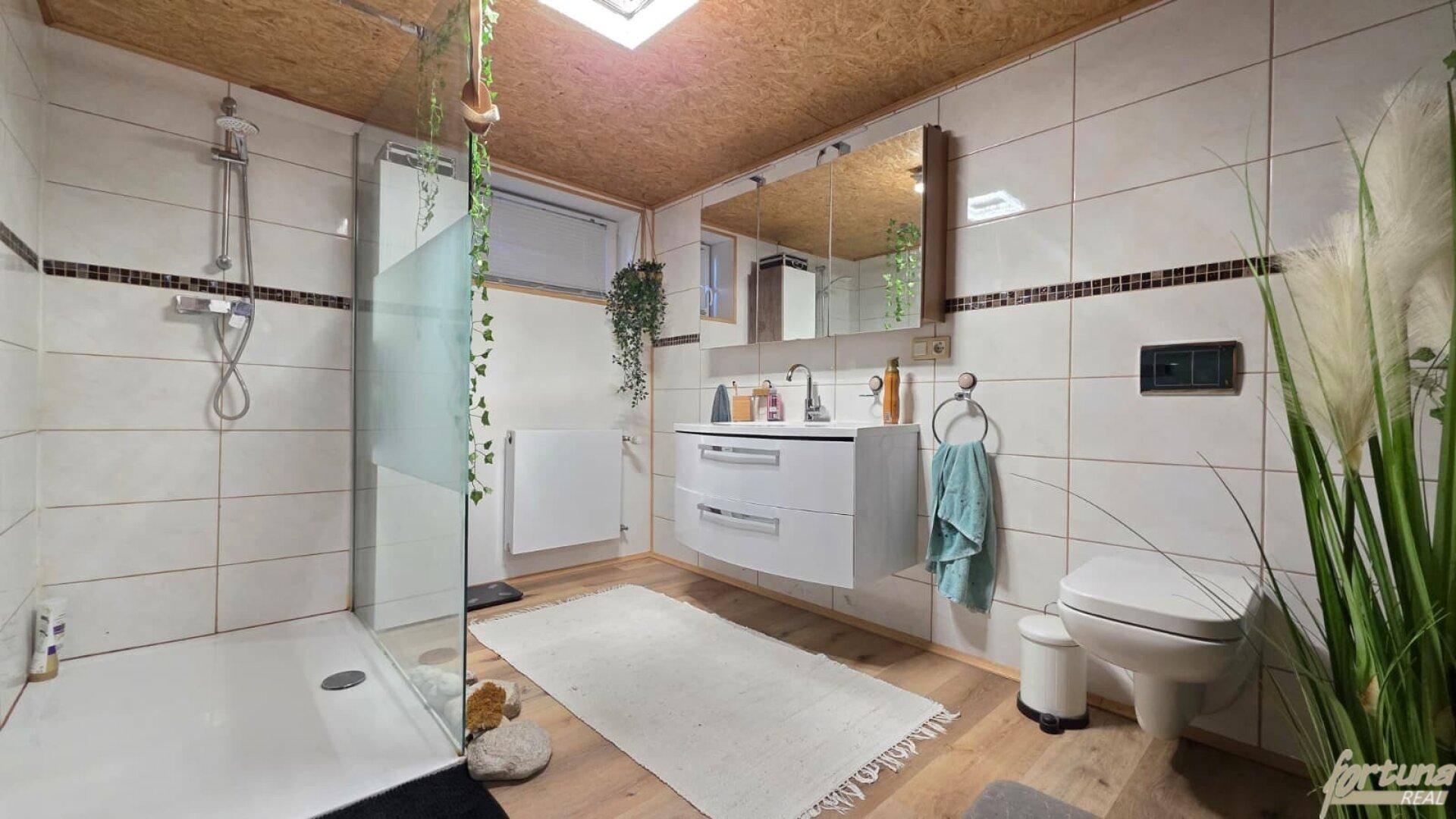 Modernes Badezimmer mit begehbarer Dusche, Waschtisch und Holzdecke, hell gefliest.