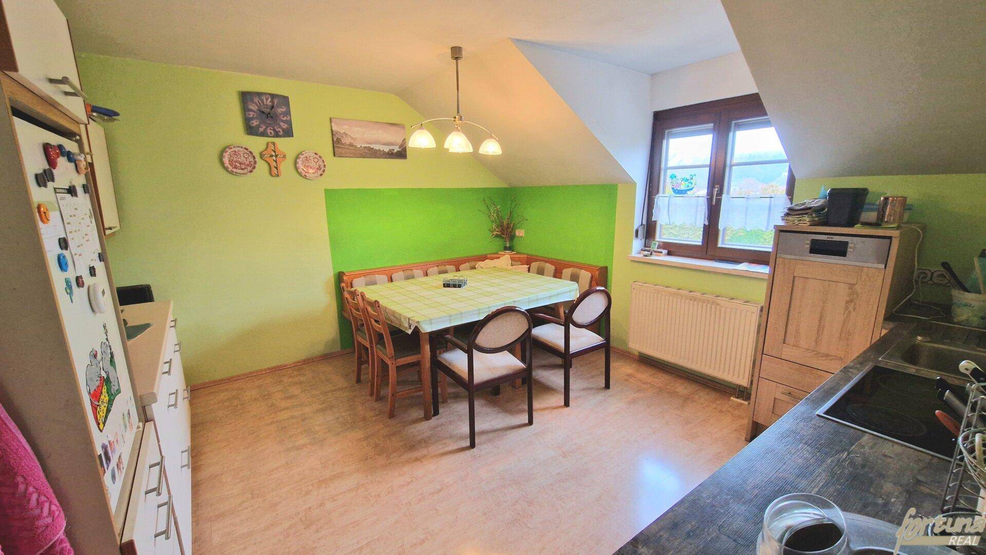 Dachgeschossküche mit Essecke, grünen Wänden und Dachschrägen, hell und einladend.