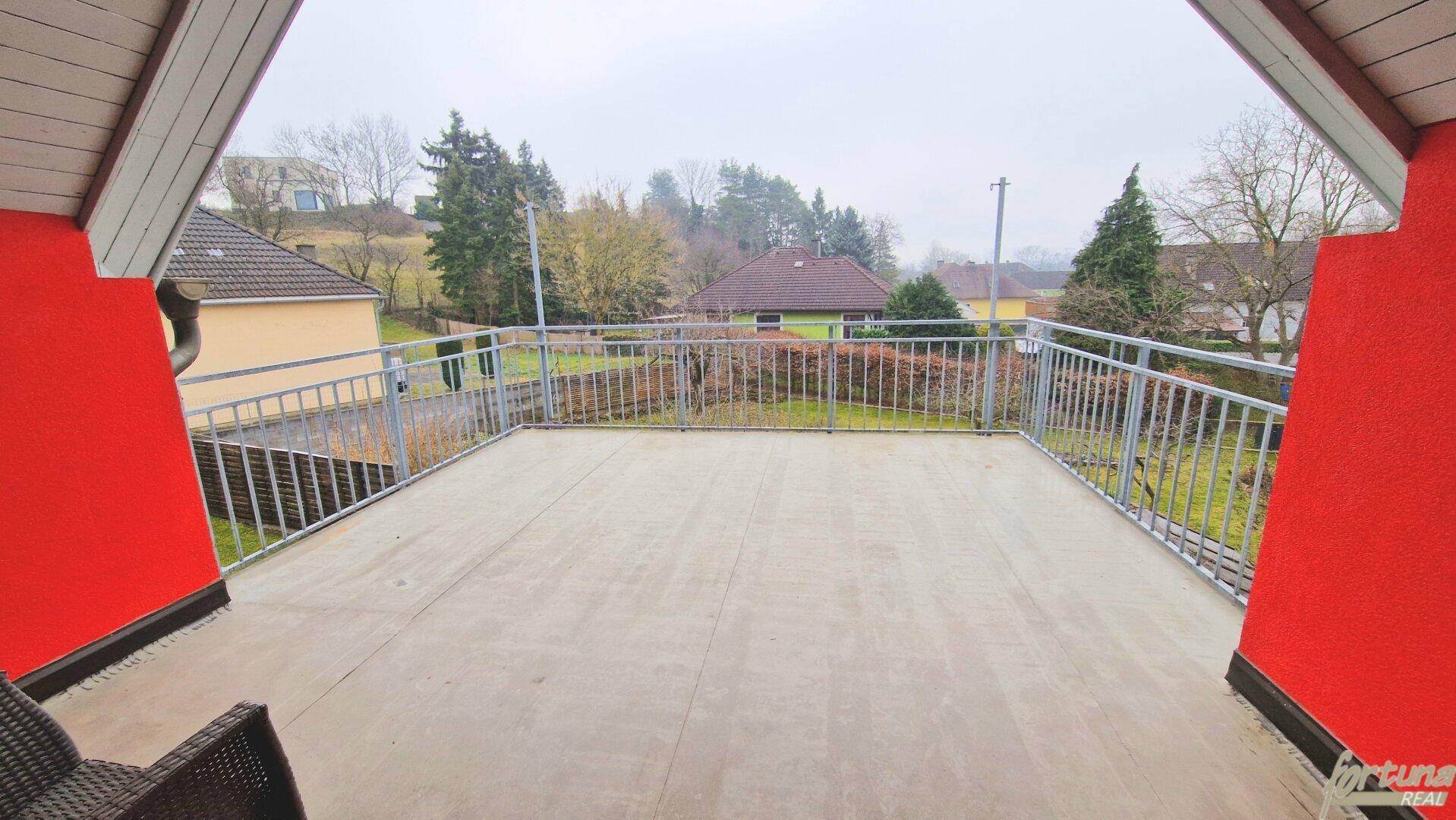 Großer Balkon mit Metallgeländer und weitem Blick in die ländliche Umgebung.