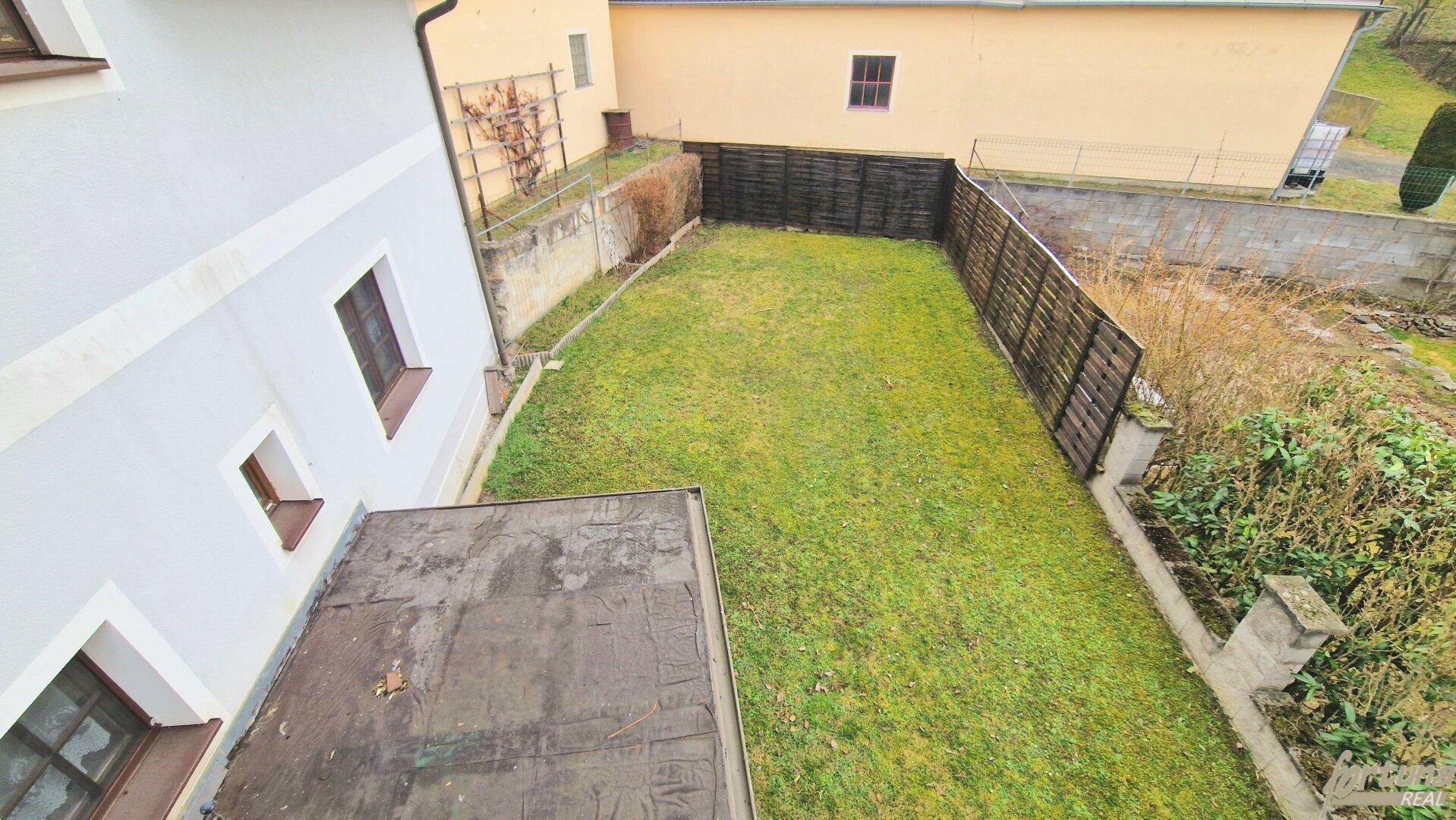 Blick von oben auf den grünen Rasenbereich des Gartens mit Holzzaun, bietet viel Platz.