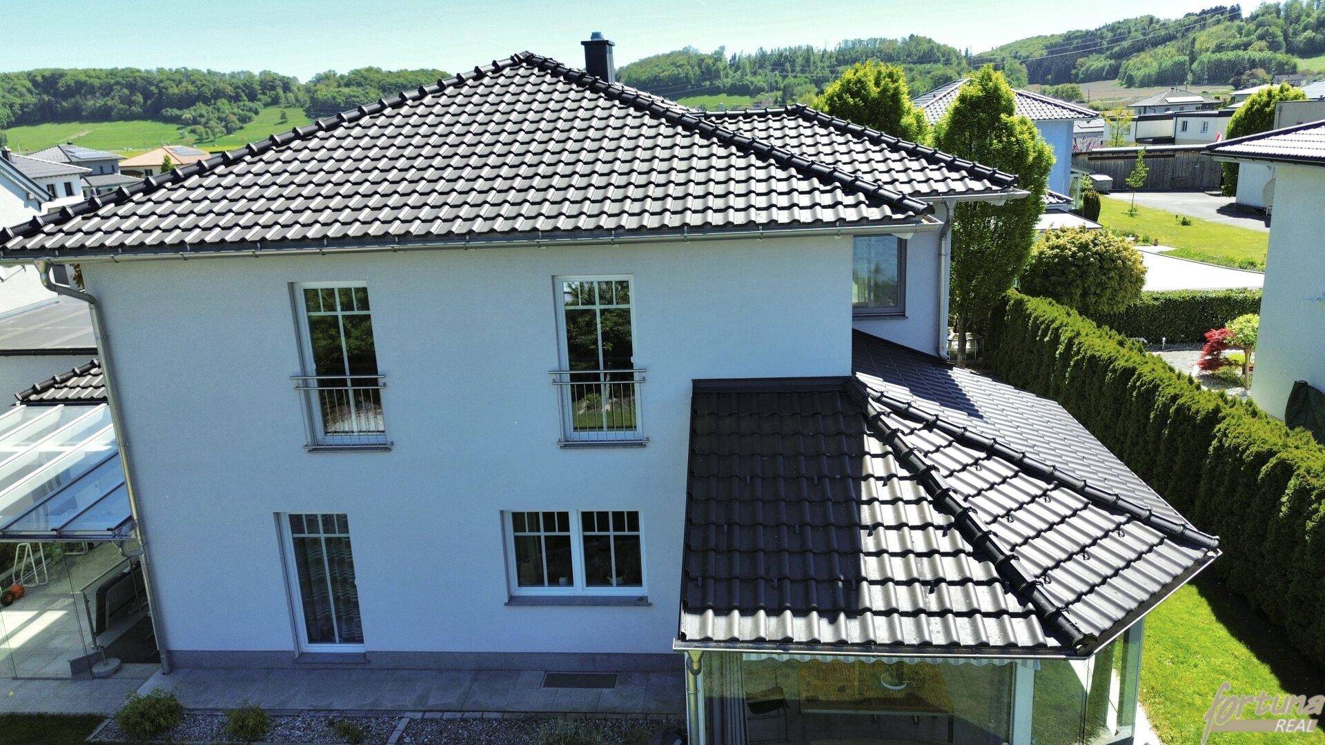 Rückansicht des Hauses mit großen Fenstern, französischen Balkonen und gepflegtem Gartenbereich.