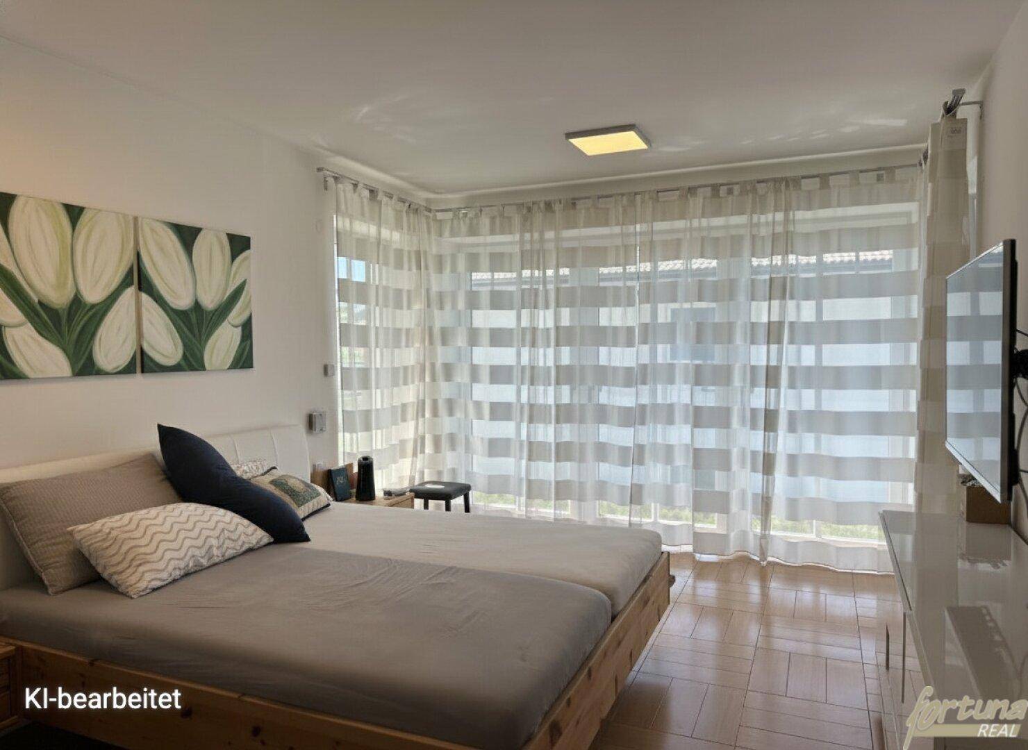 Gemütliches Schlafzimmer mit Holzbett, großen Fenstern und hellem Parkettboden.