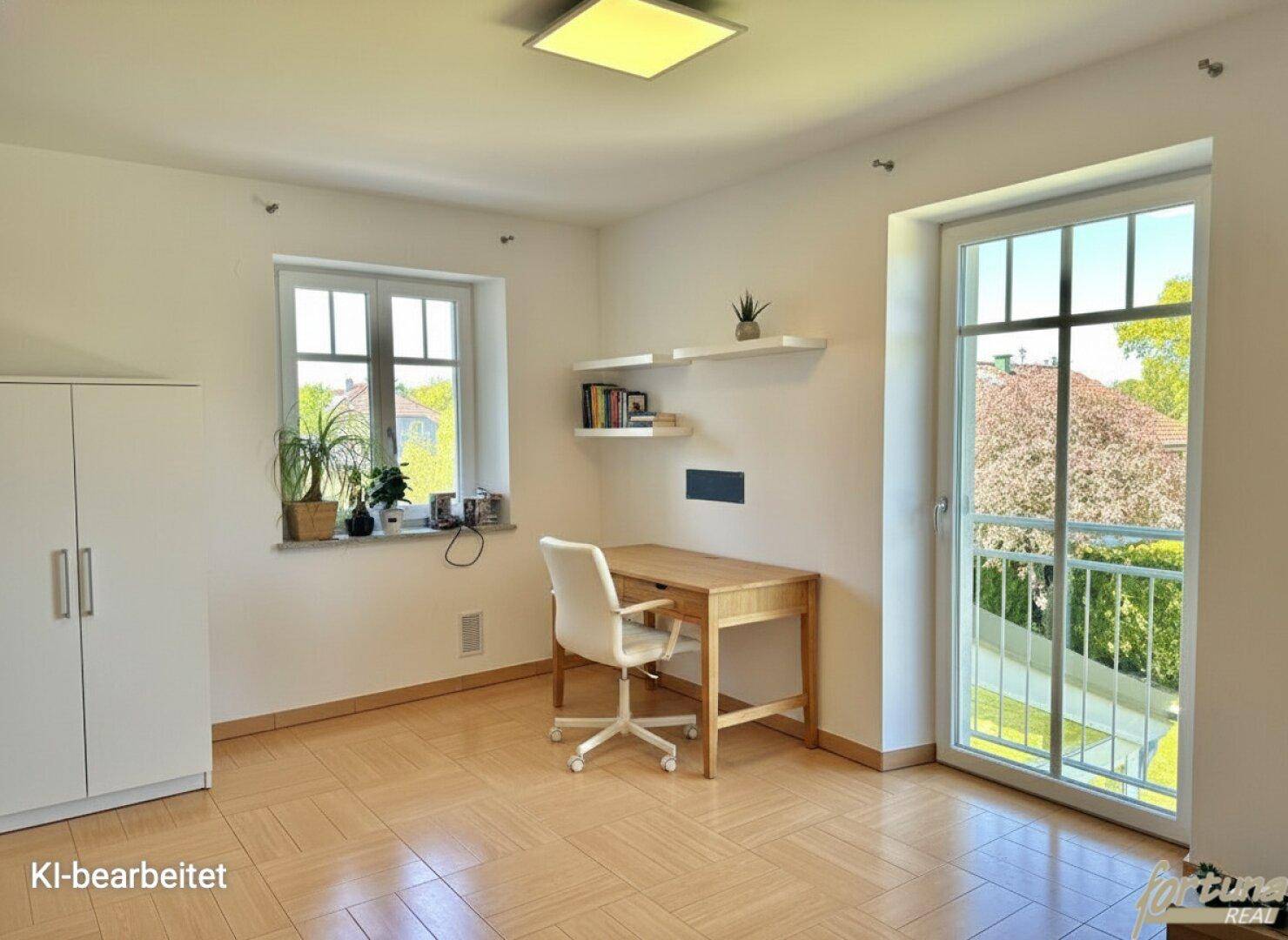Helles Arbeitszimmer mit Schreibtisch, Schrank und Zugang zu einem französischen Balkon.