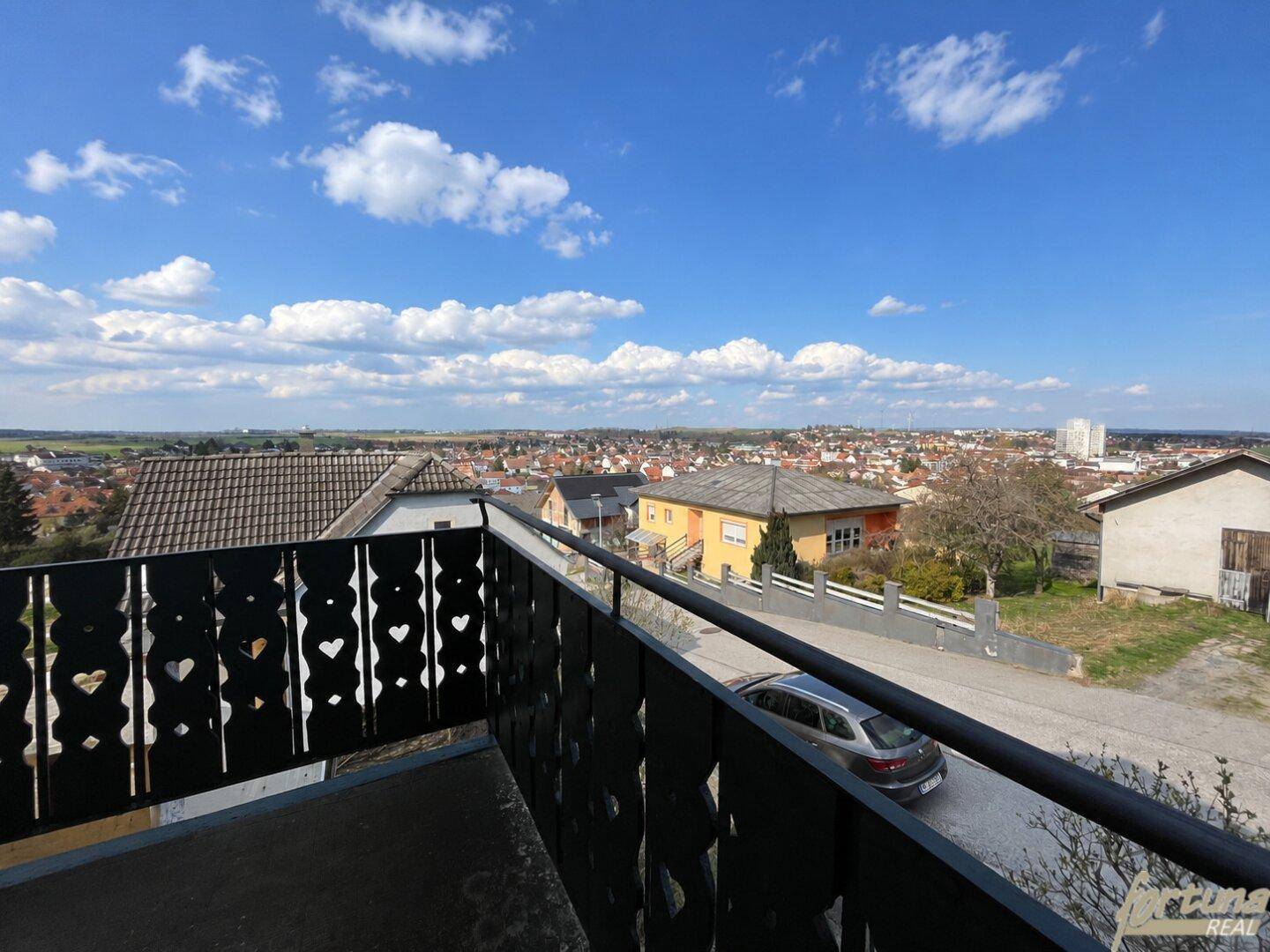 Balkon mit Blick über die Dächer der Stadt und die umliegende Landschaft.