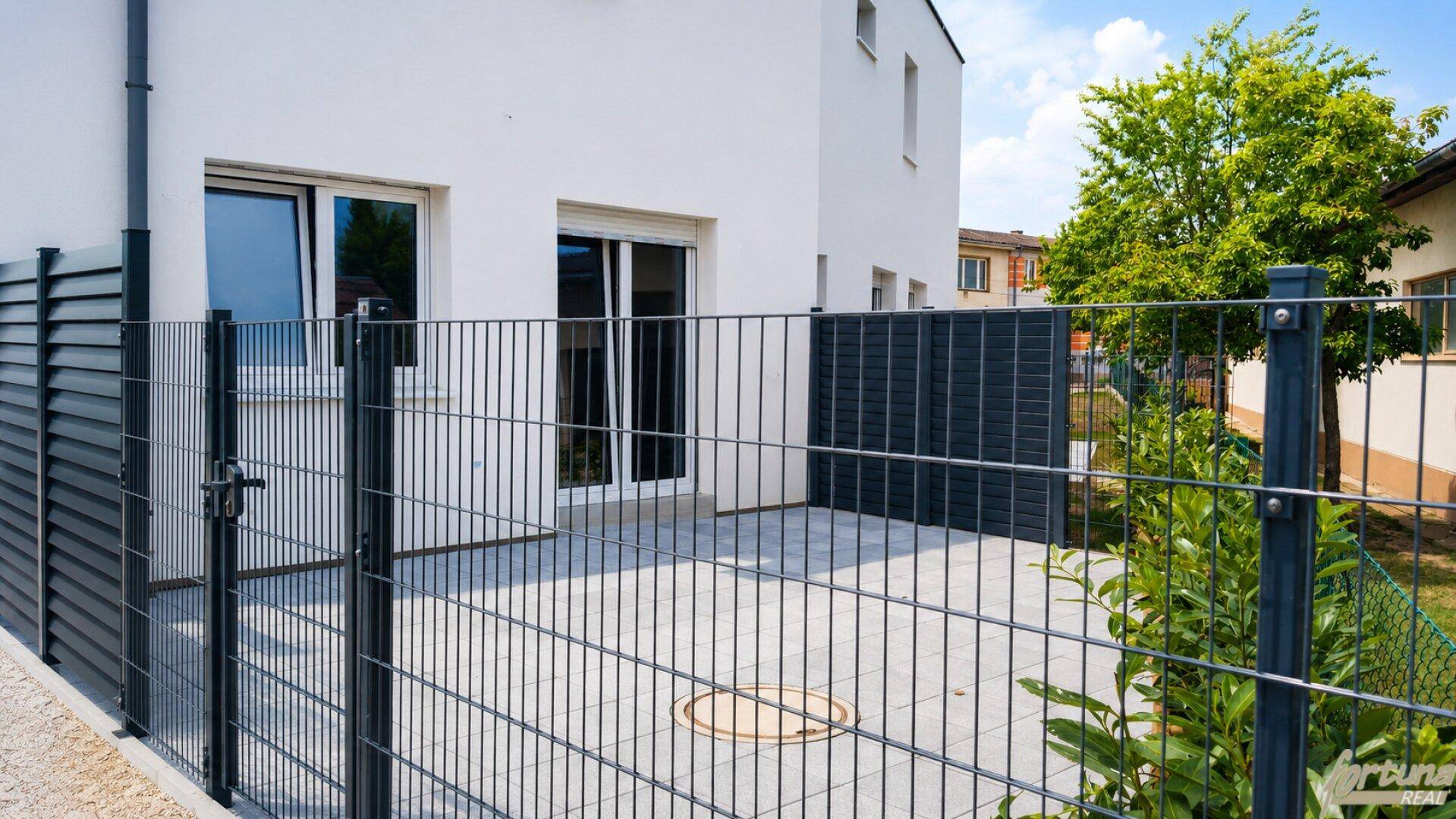 Private Terrasse mit modernem Zaun und Zugang zum Gartenbereich des Reihenhauses.