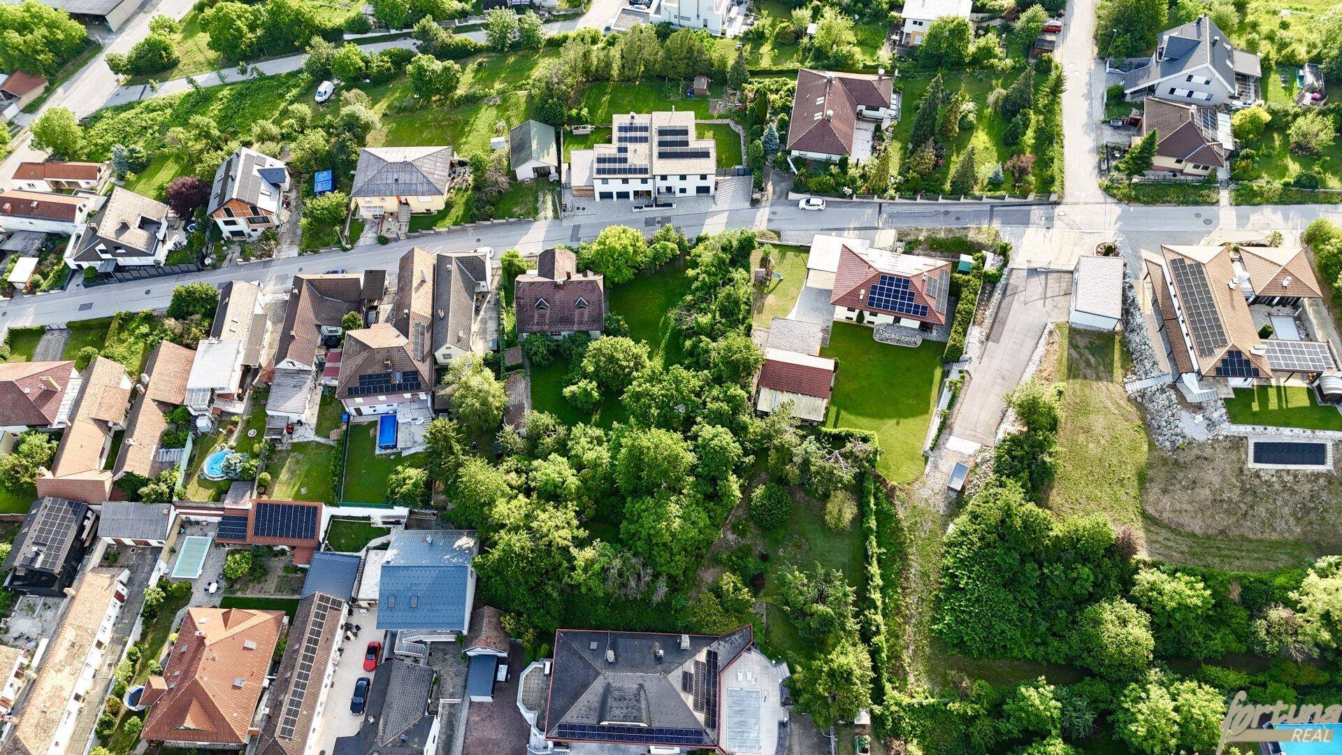 Weitläufige Luftaufnahme einer Wohnsiedlung mit vielen Häusern und Grünflächen.